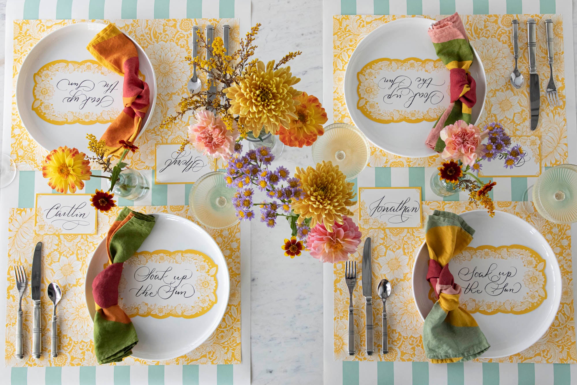 A vibrant table setting for four featuring Spring Blooms Table Cards resting on each plate, from above.