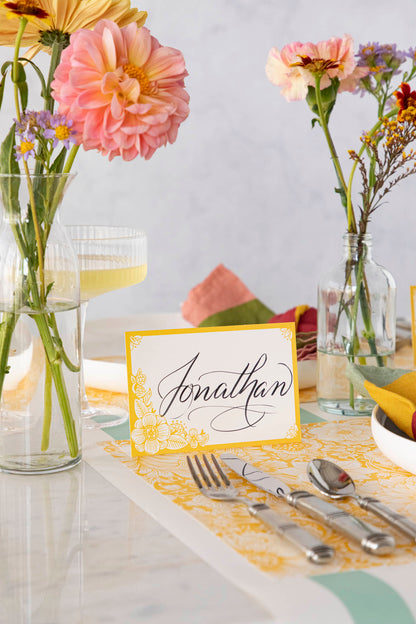 An elegant floral place setting featuring a Spring Blooms Place Card labeled &quot;Jonathan&quot; standing next to the plate.
