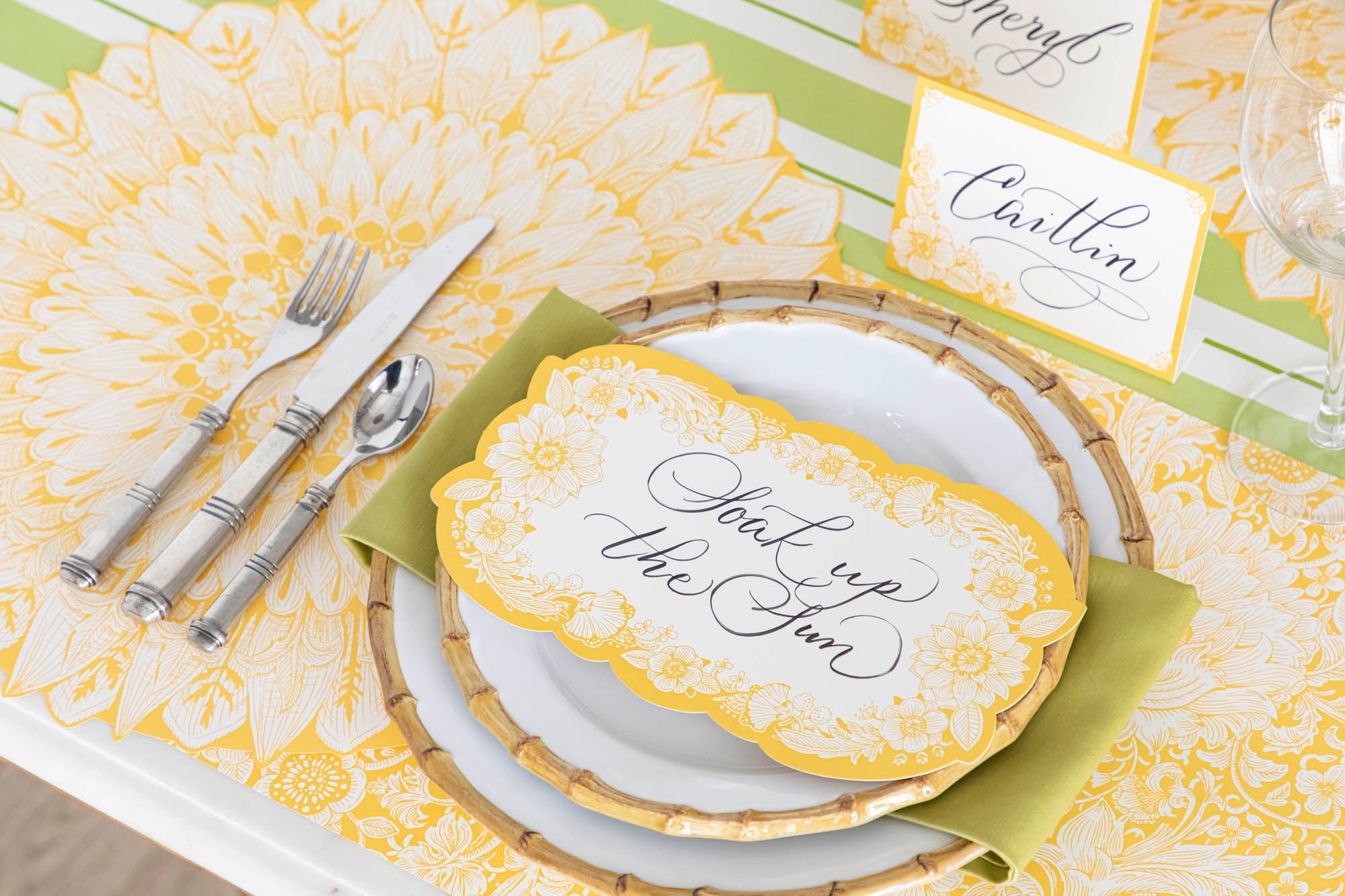 Close-up of a Spring Blooms Table Card with "Soak up the sun" written on it in lovely script resting on the plate of a vibrant place setting.