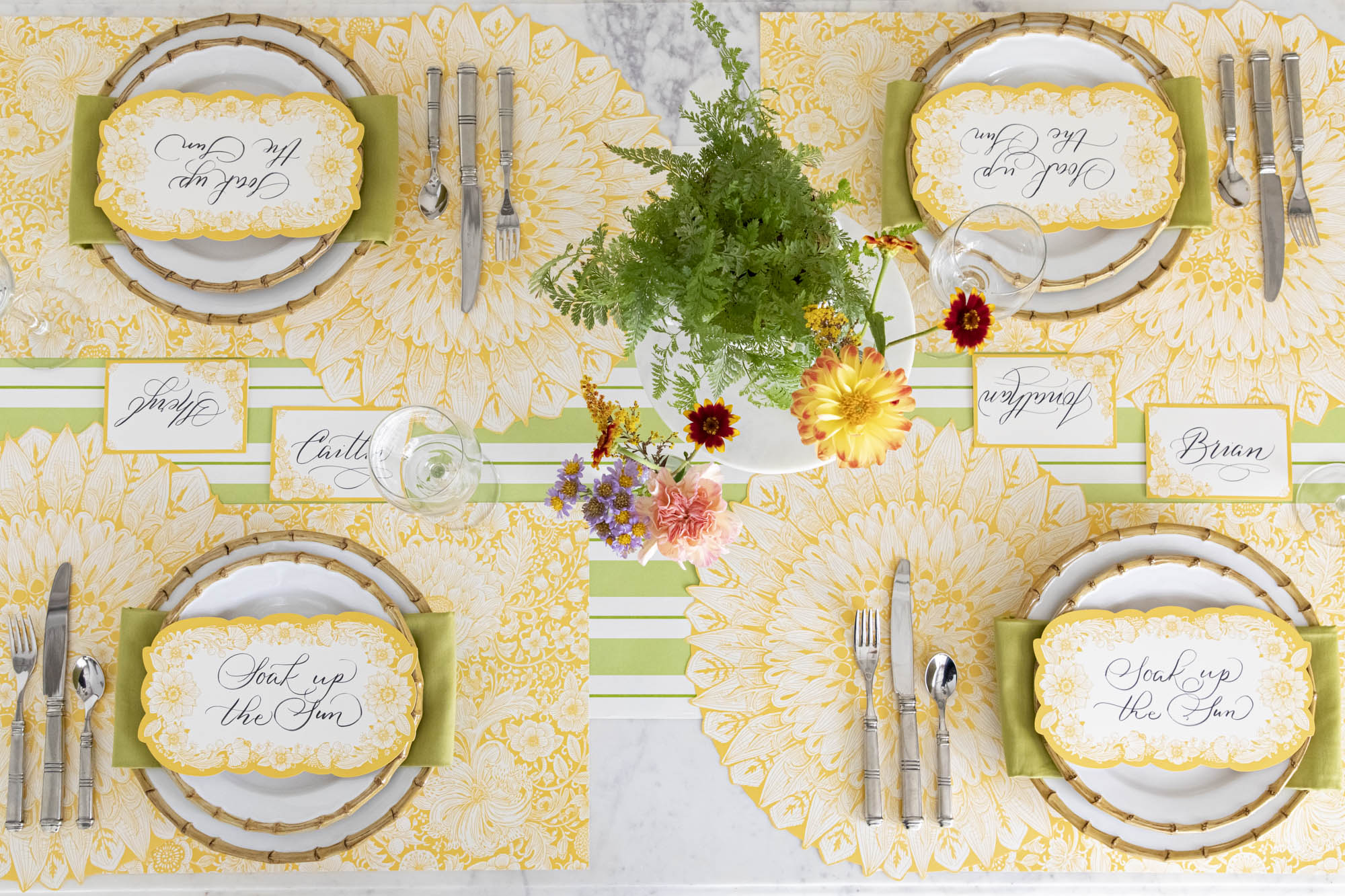 A vibrant table setting for four featuring Spring Blooms Table Cards resting on each plate, from above.