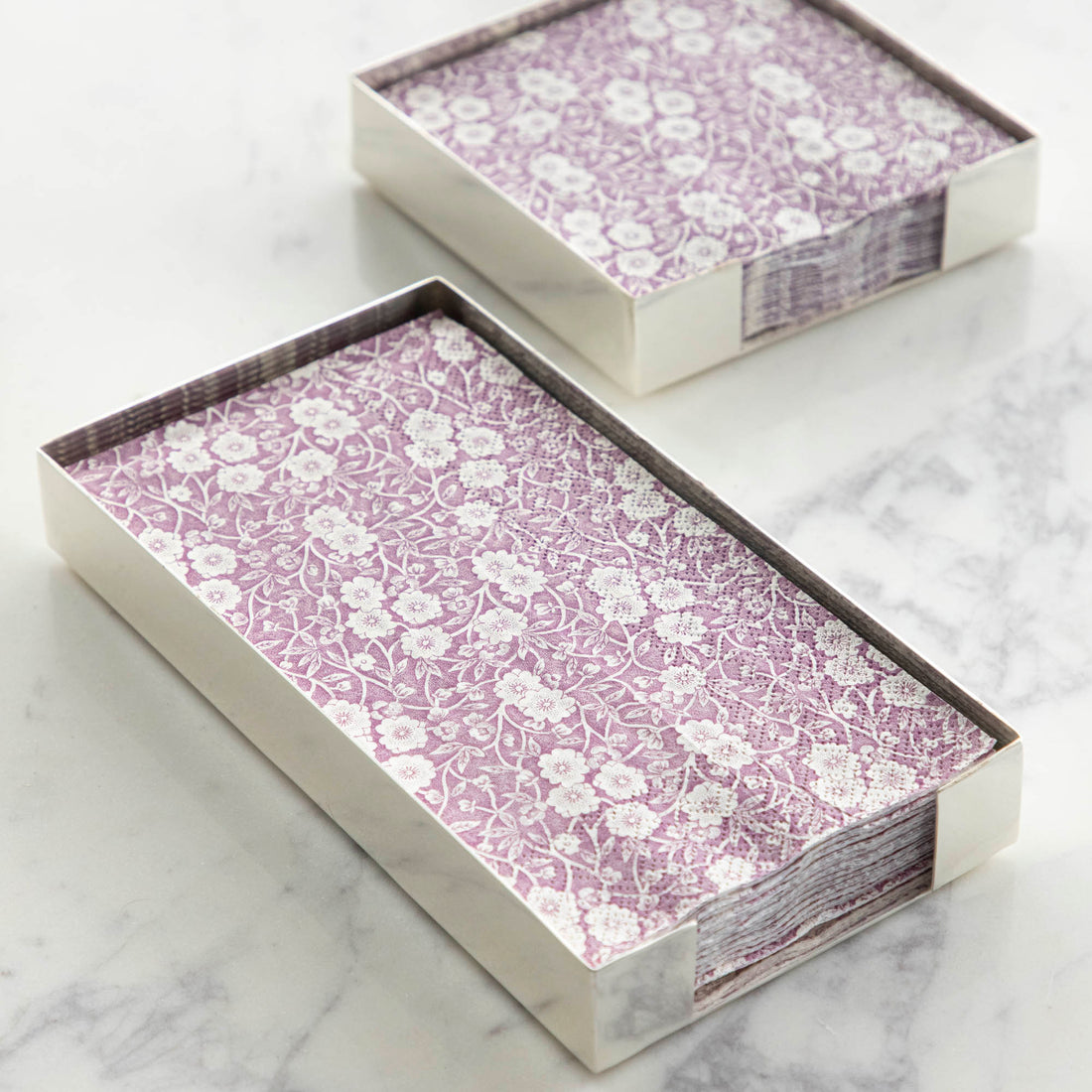 Two Silver Napkin Holders, guest-sized and cocktail-sized, containing purple and white napkins on a white table.