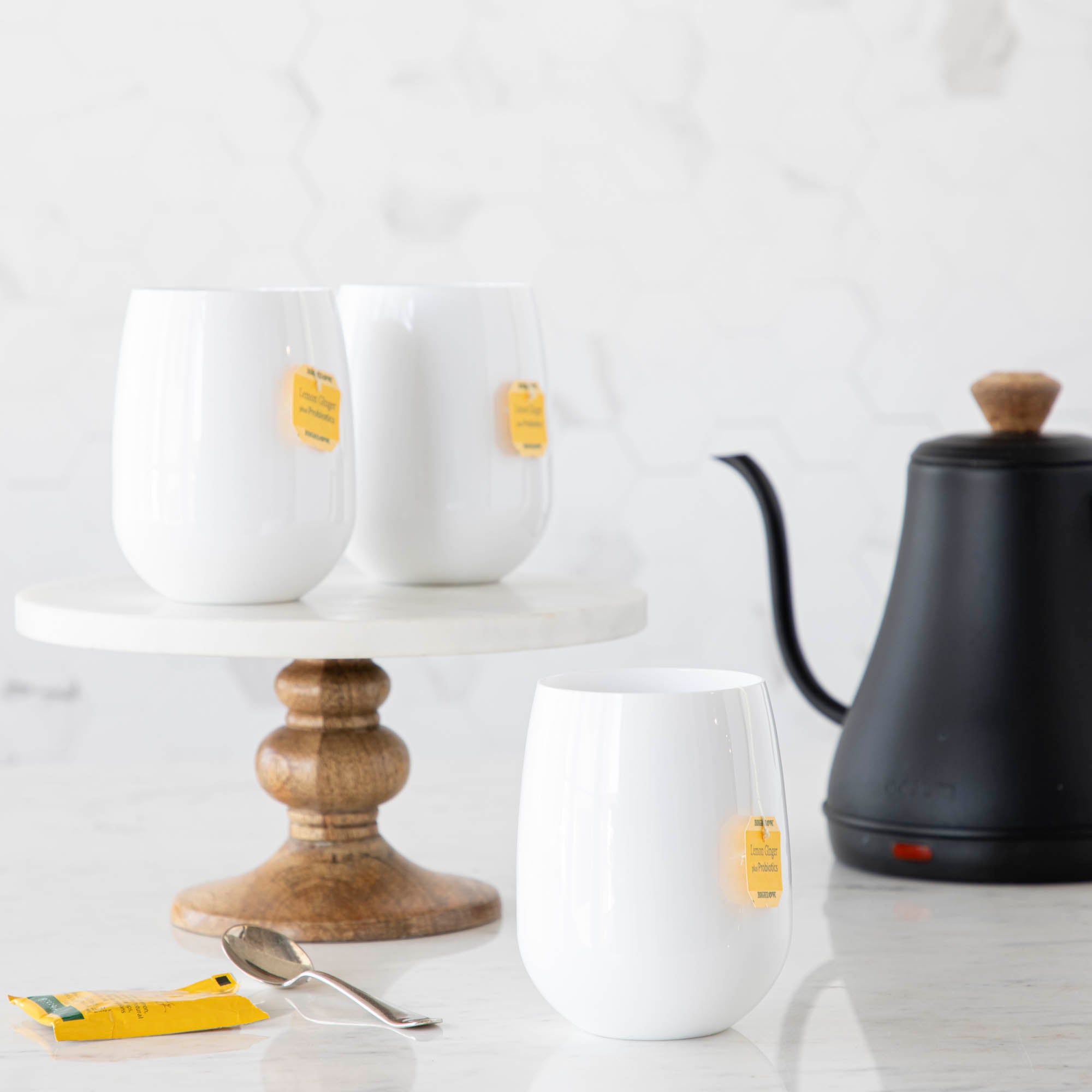 3 SymGlasses with tea bags in them and a tea kettle in the background.