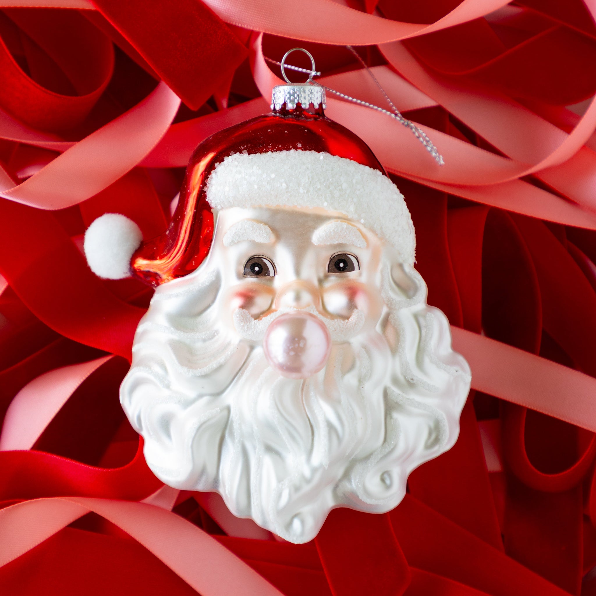 Glass Bubblegum Santa Ornament on top of red ribbon.