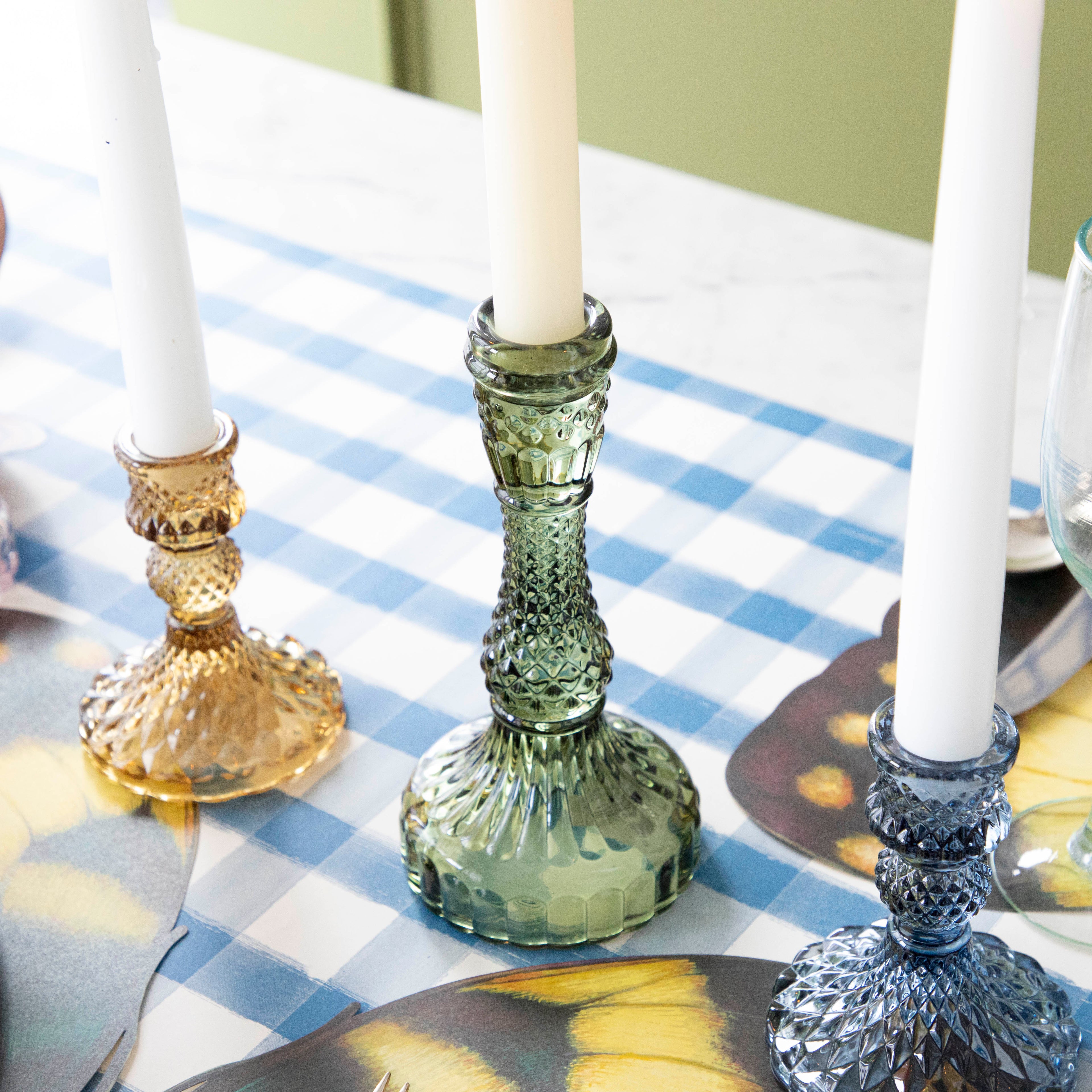 A yellow, green and blue candlestick on a set table.