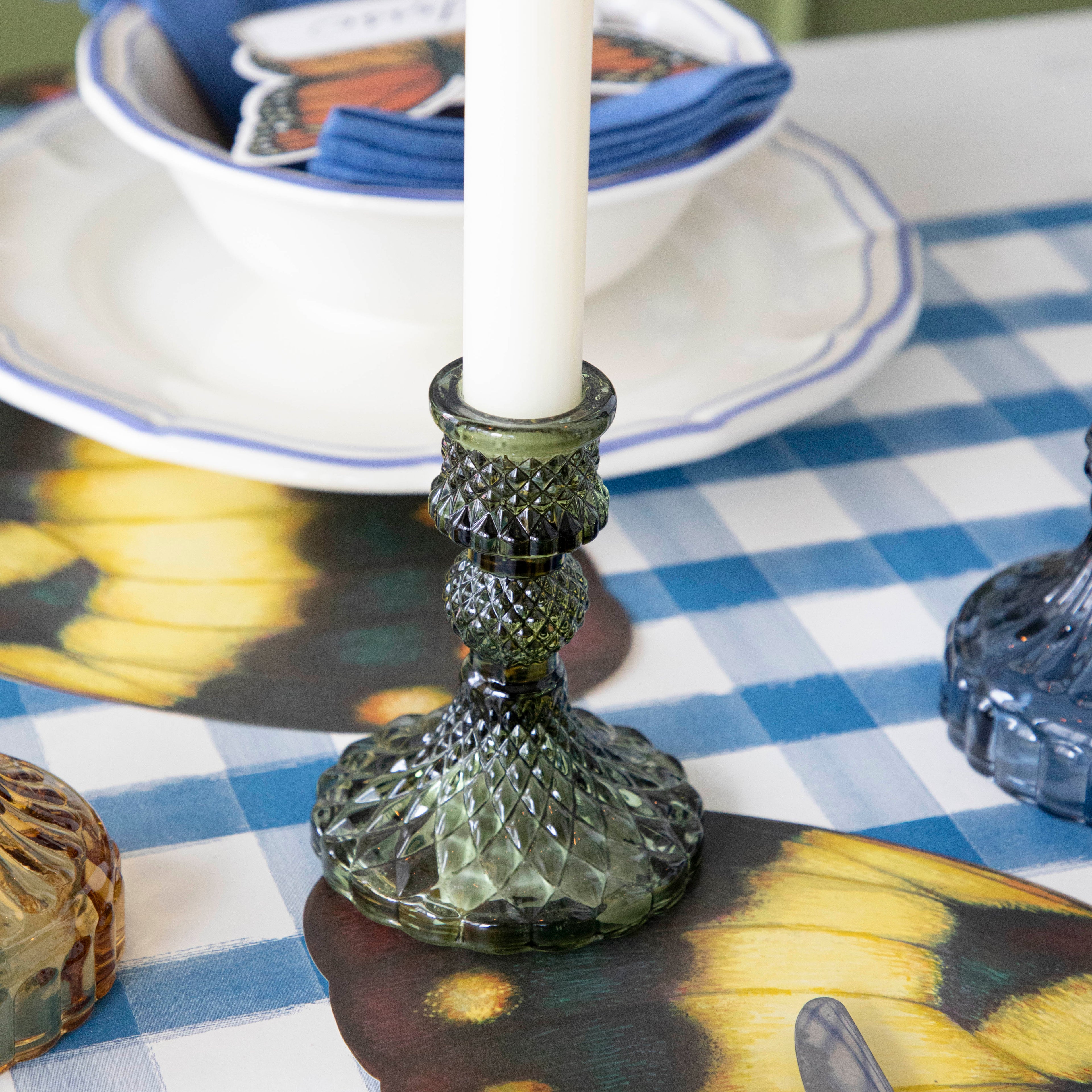 A green candle holder on a set table.