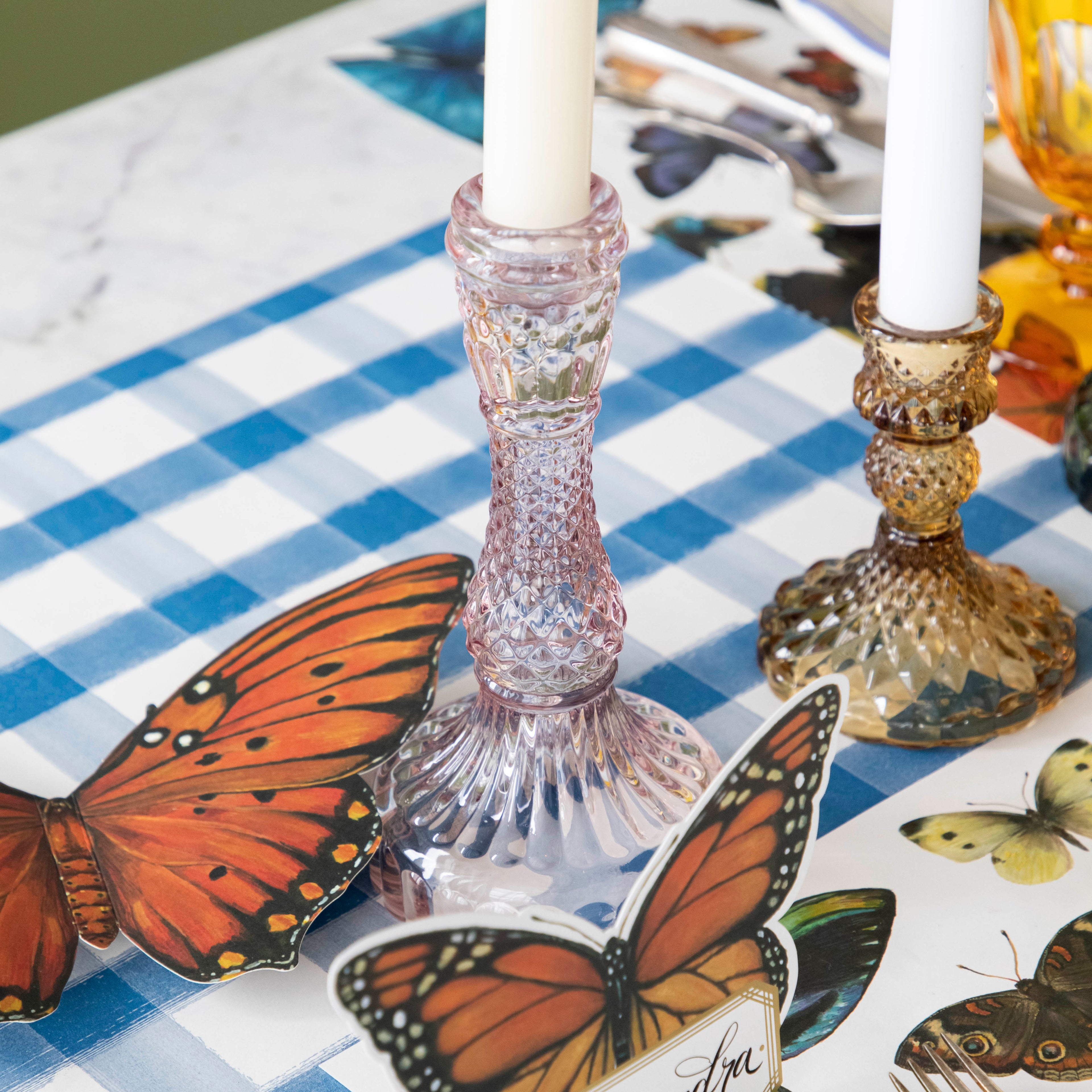 A pink glass candlestick on a set table.