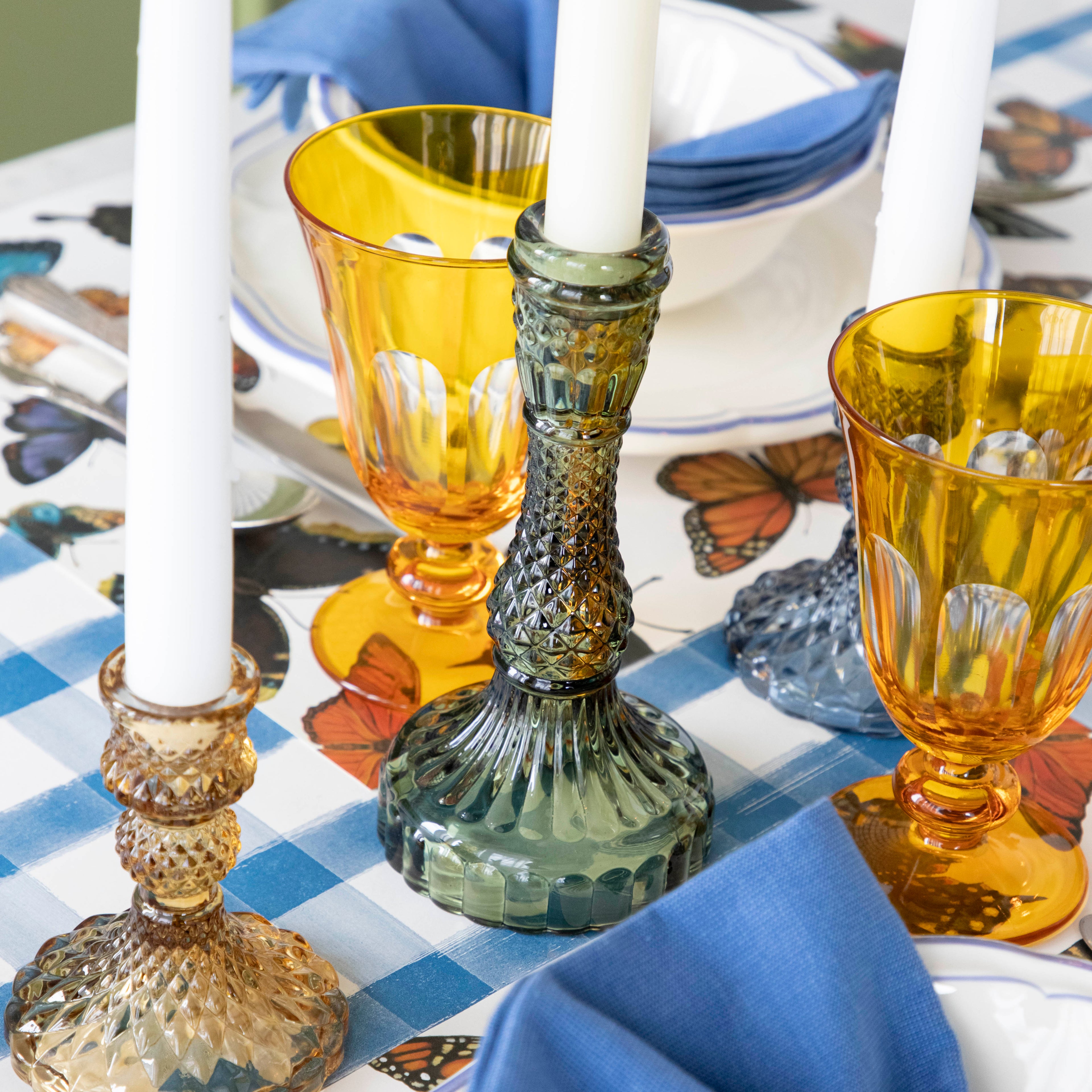 A green candle holder on a set table.