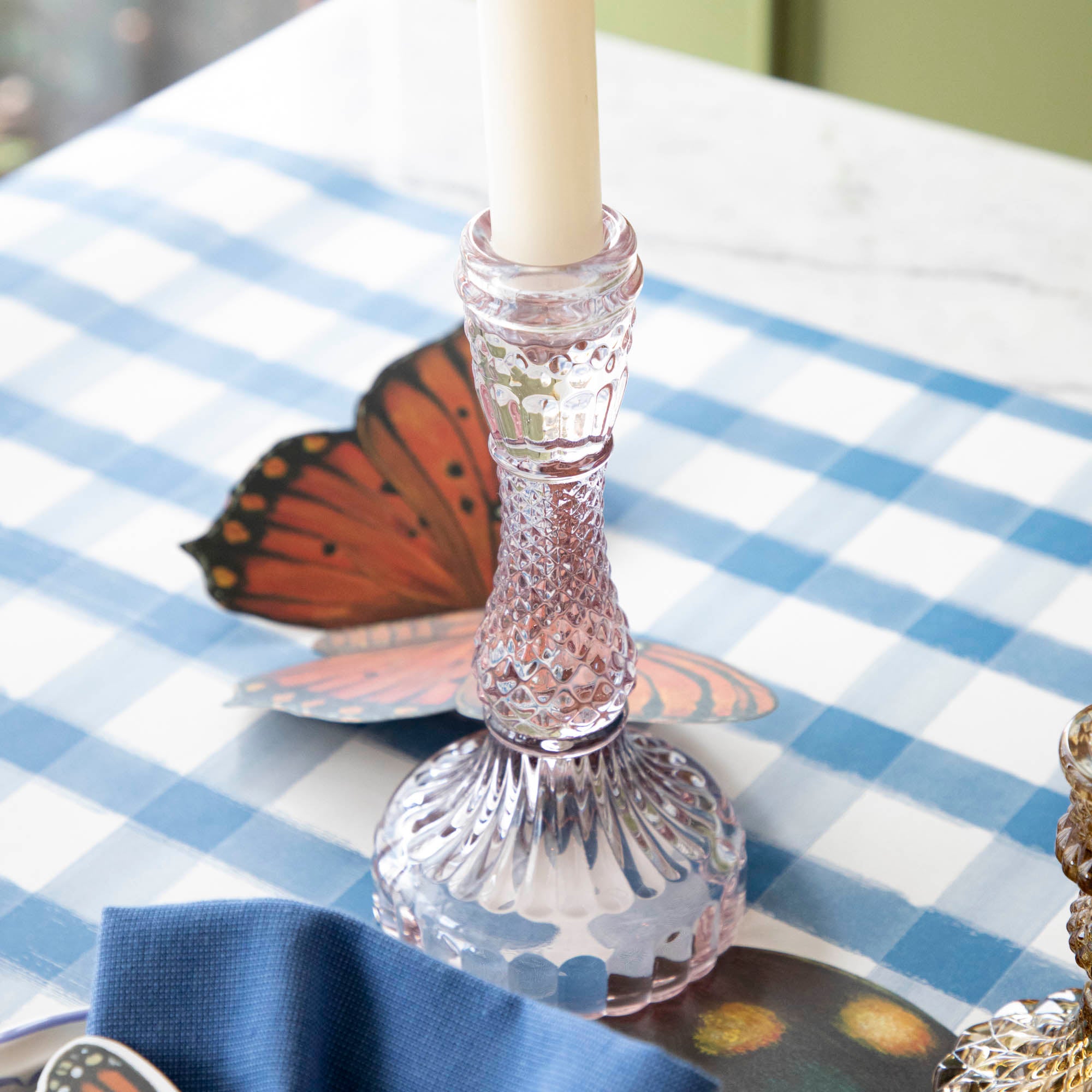 A pink glass candlestick on a set table.