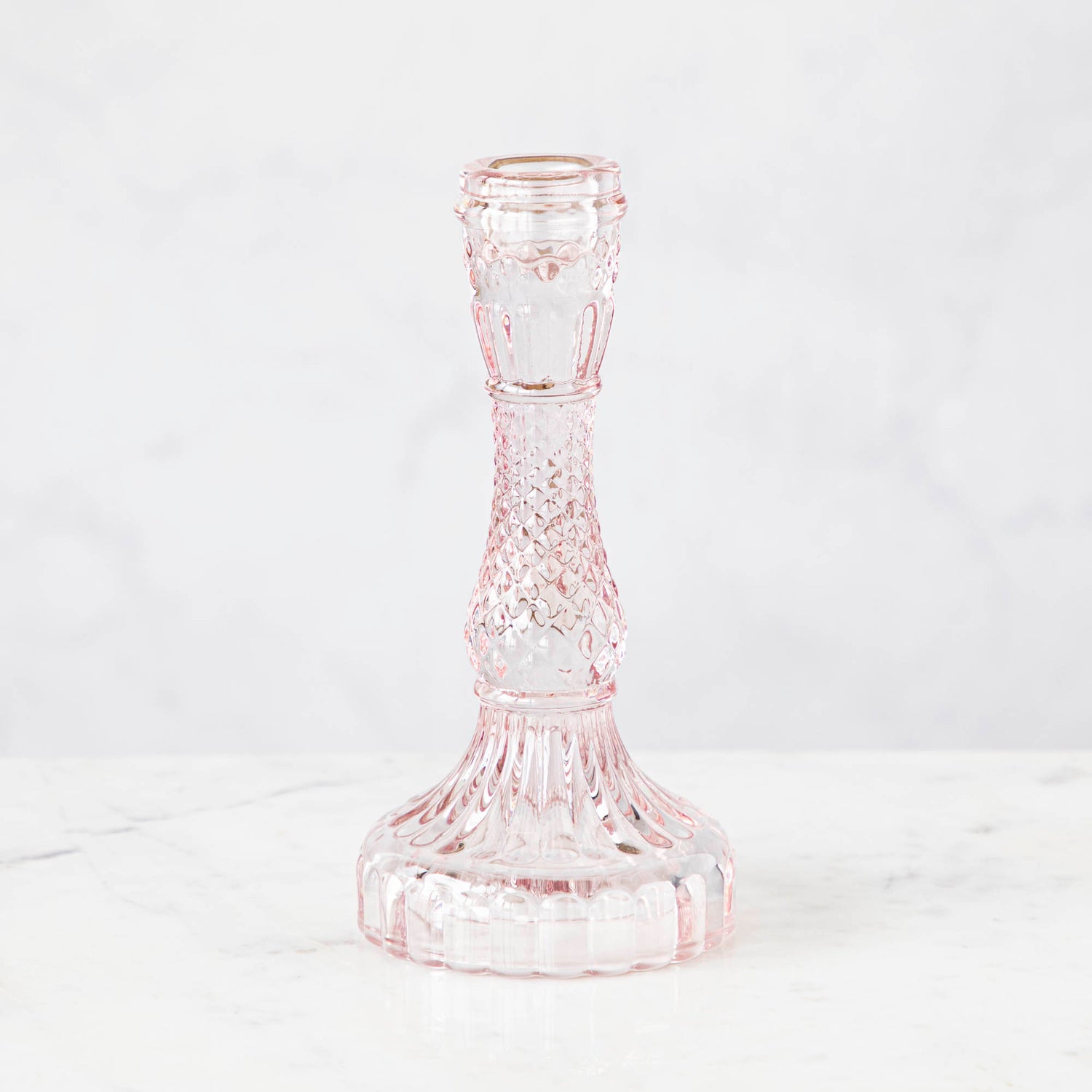 A pink glass candlestick on a white background.