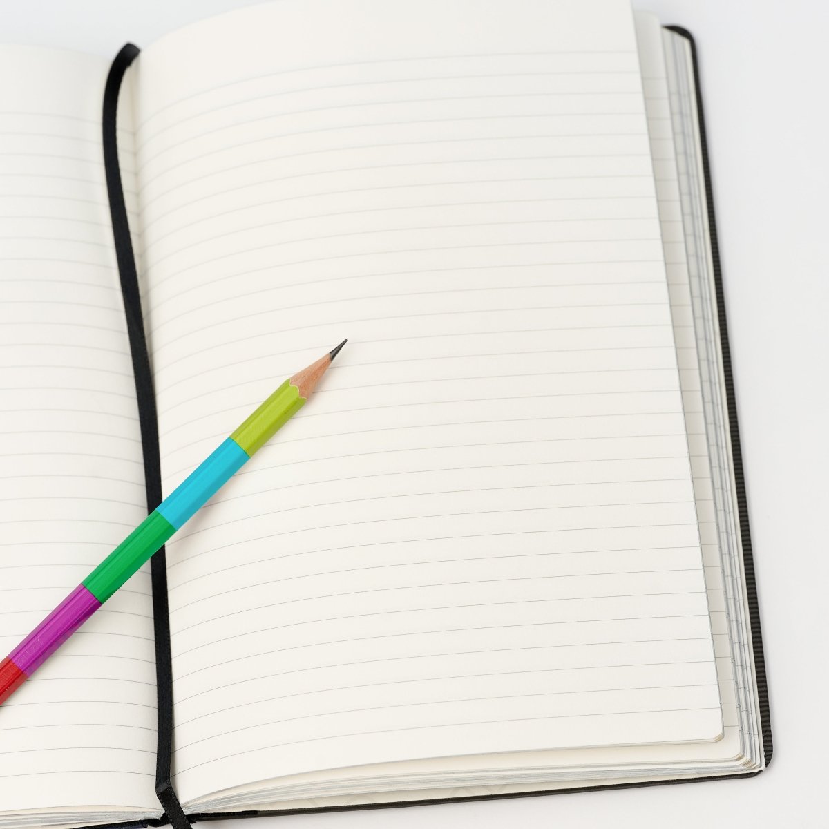 Colorful pencil on an open notebook with a white background.