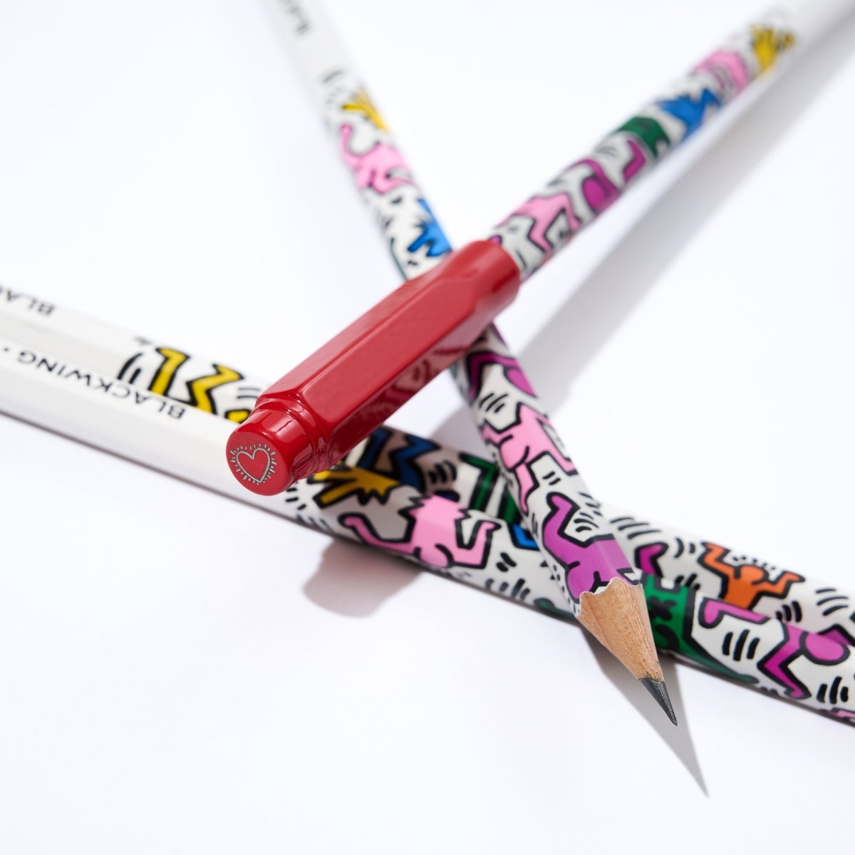 Colorful pencils with Keith Haring-style designs on a white background.