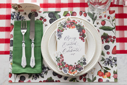 Top-down view of a berry-themed place setting featuring a Berry Bramble Table Card with &quot;Berry Excited to Celebrate&quot; written on it in lovely script.