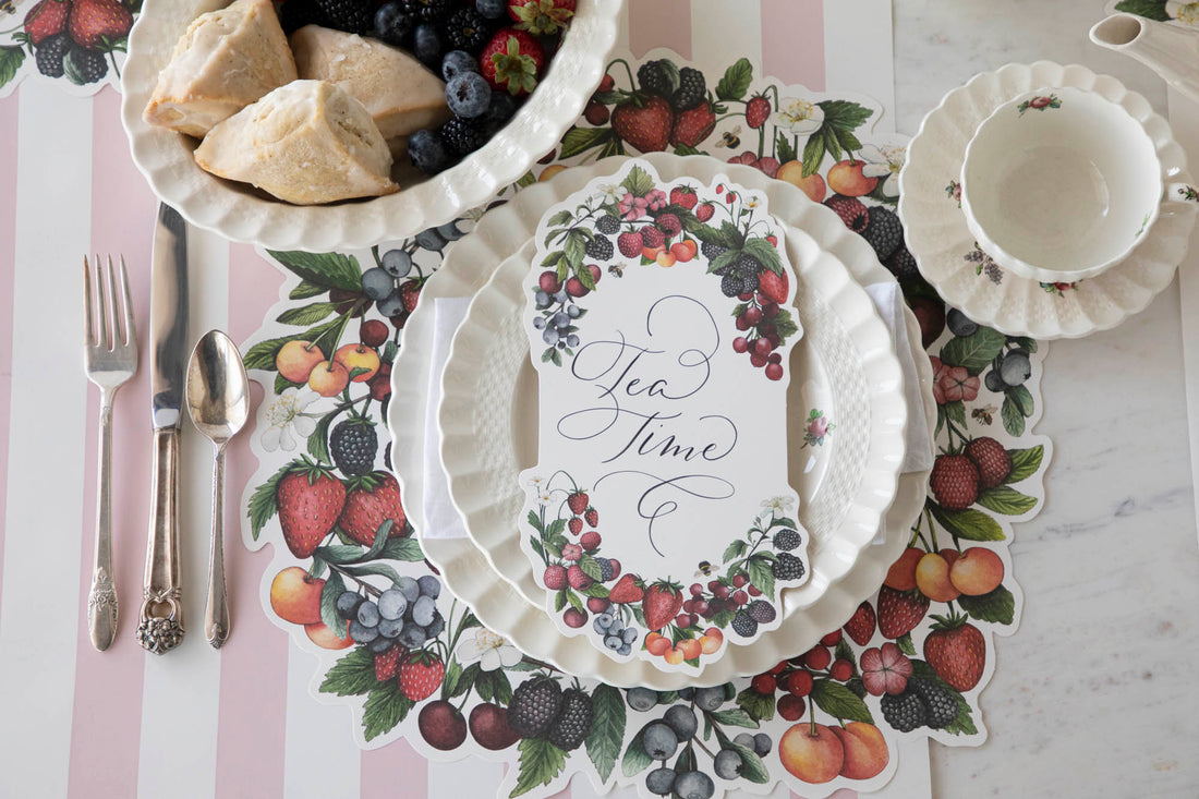 A Berry Bramble Table Card with &quot;Tea Time&quot; written on it in beautiful script resting on the plate of a summertime place setting, from above.
