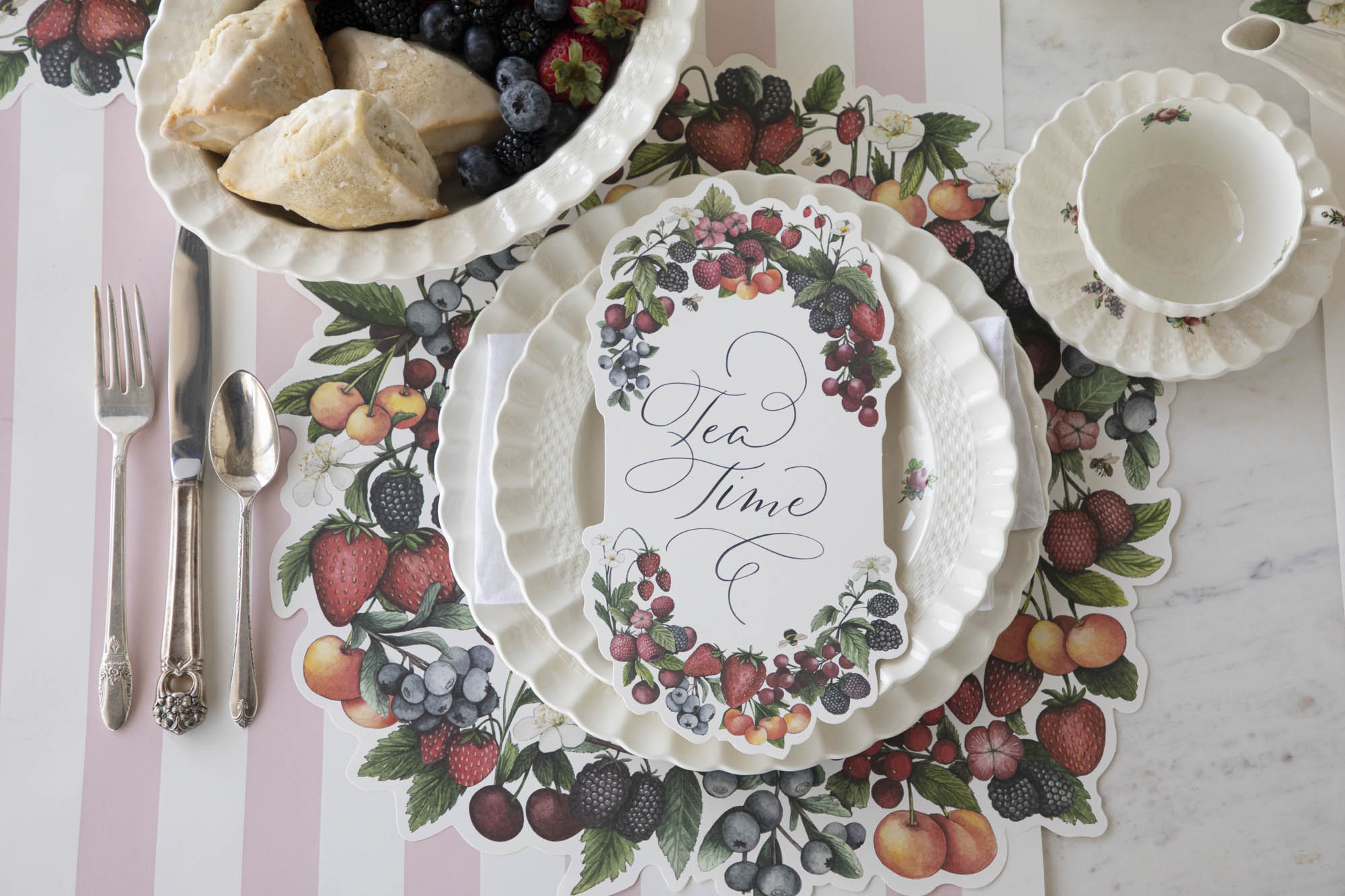 A Berry Bramble Table Card with &quot;Tea Time&quot; written on it in beautiful script resting on the plate of a summertime place setting, from above.