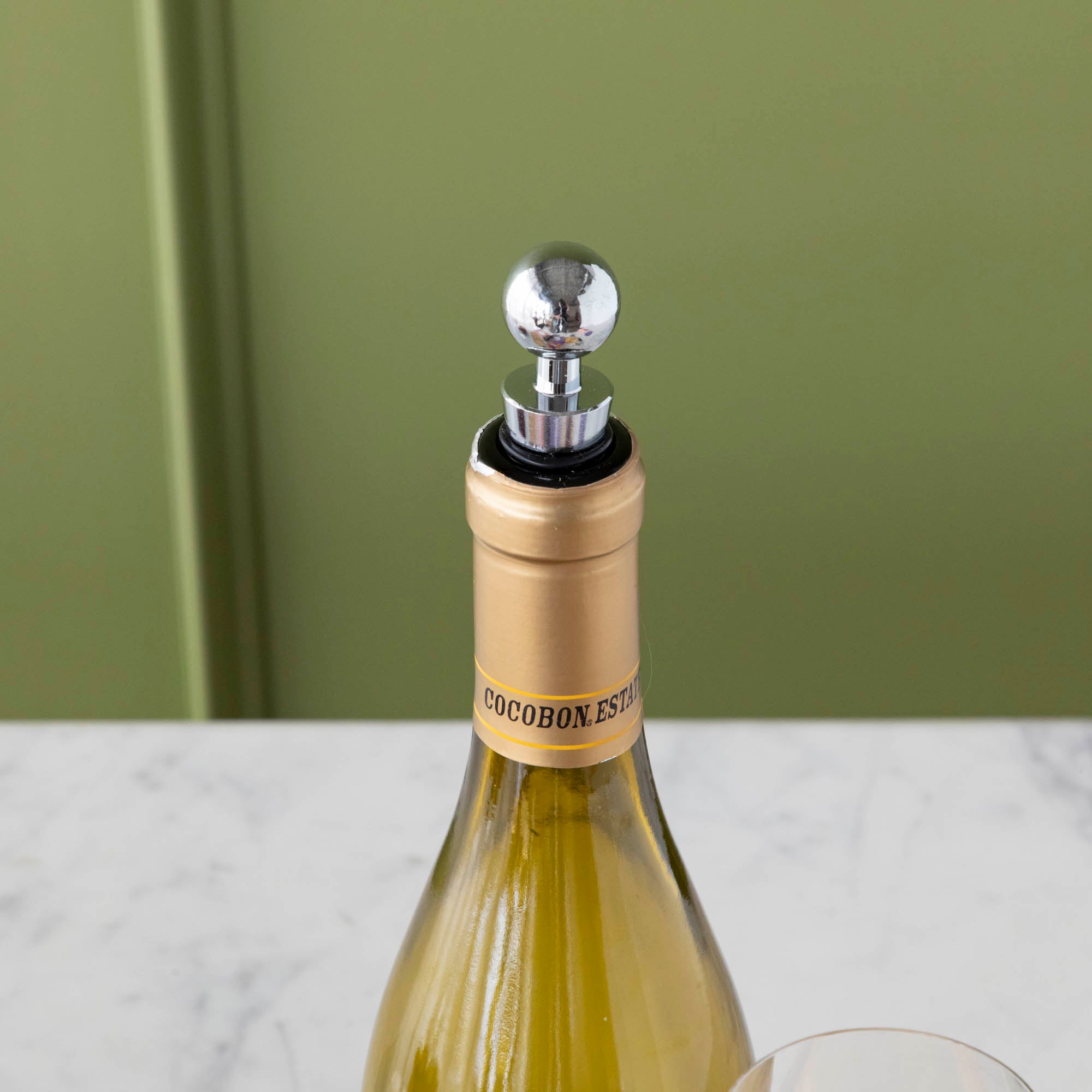 A gift set for wine nights displayed on a table, including a corkscrew, a bottle stopper, a glass of wine, a bottle of wine, bread, and grapes. The set comes in a colorful box with conversation starter cards visible.