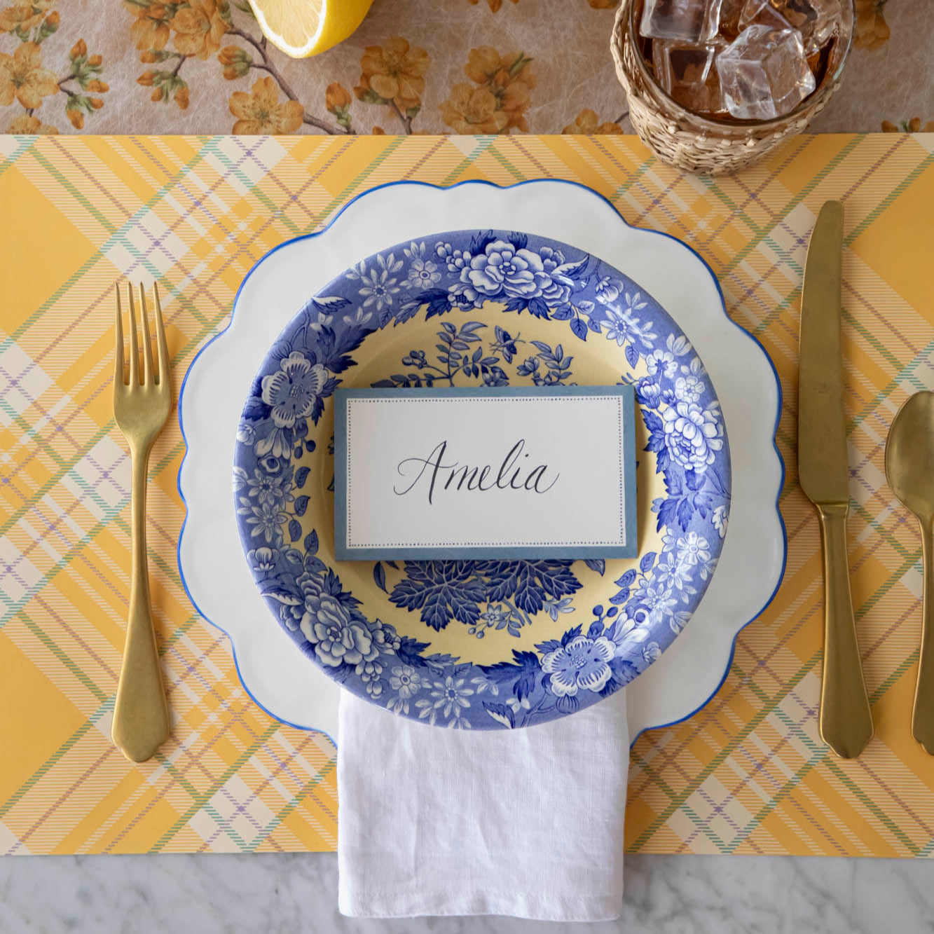 Cornflower Blue Place Card with "Amelia" written on it, centered on plates on a place setting for one.