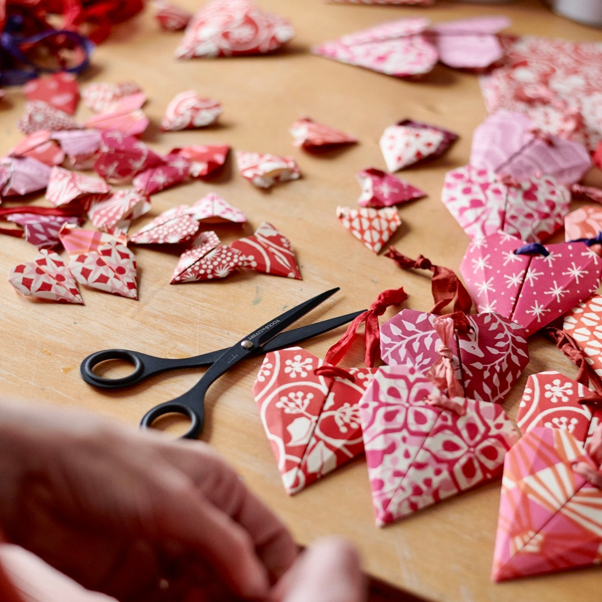 Red and pink origami hearts being crafted.