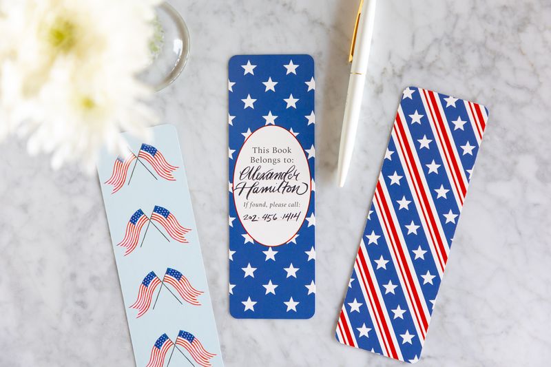 Three personalized bookmarks with American flag designs on a marble surface.