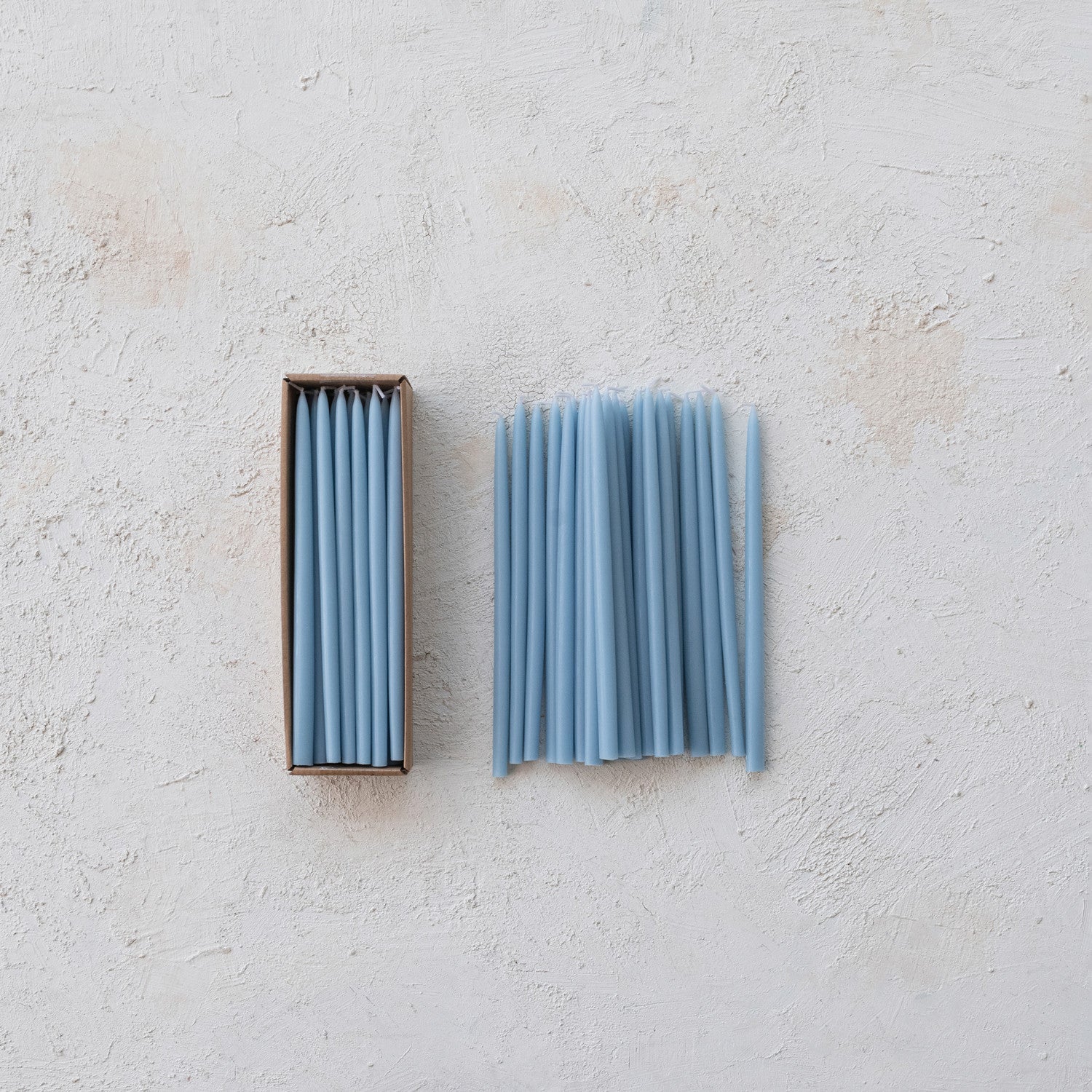 Set of blue candles with a box on a light gray background