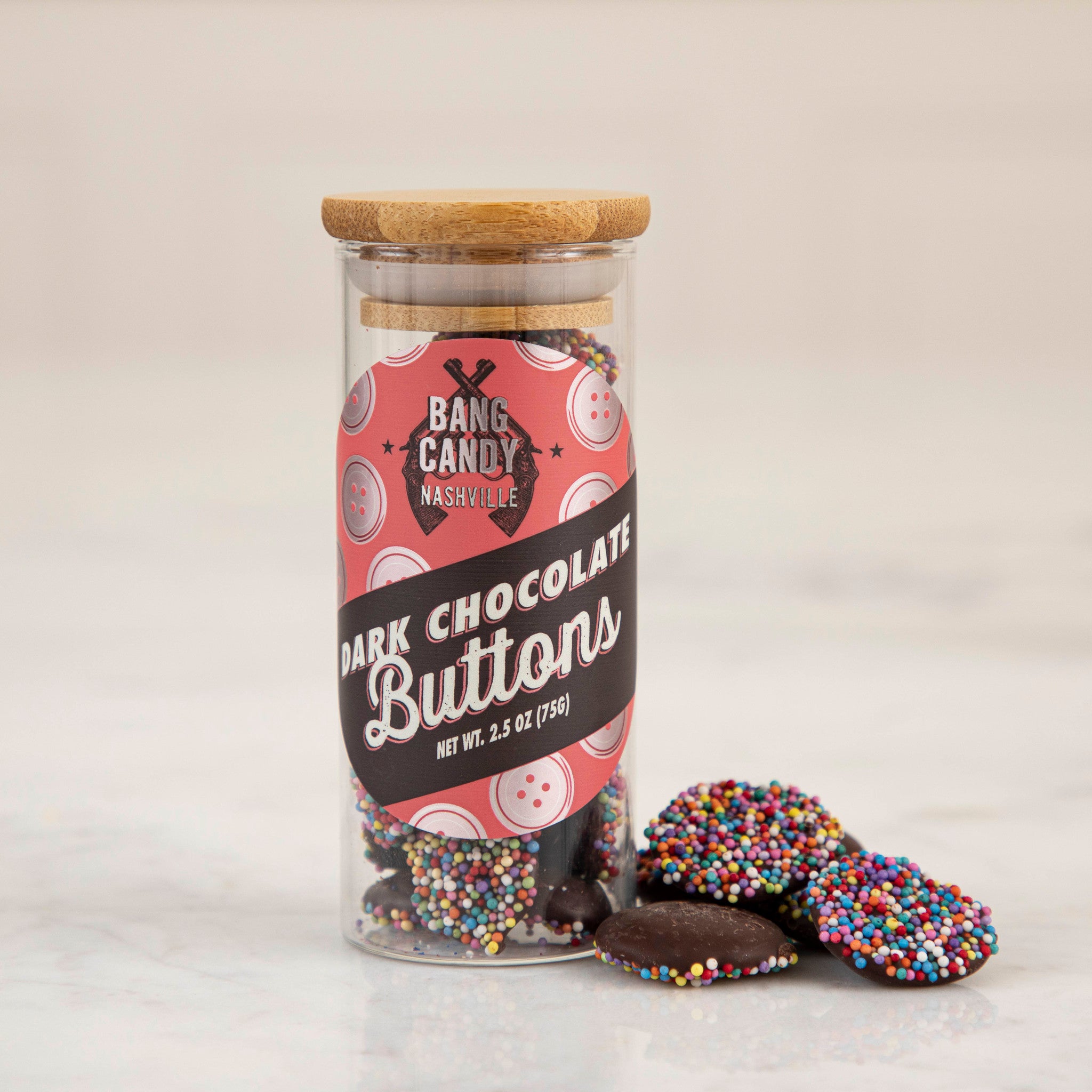 A jar of Hester & Cook chocolate buttons with natural nonpareils sprinkled on top.