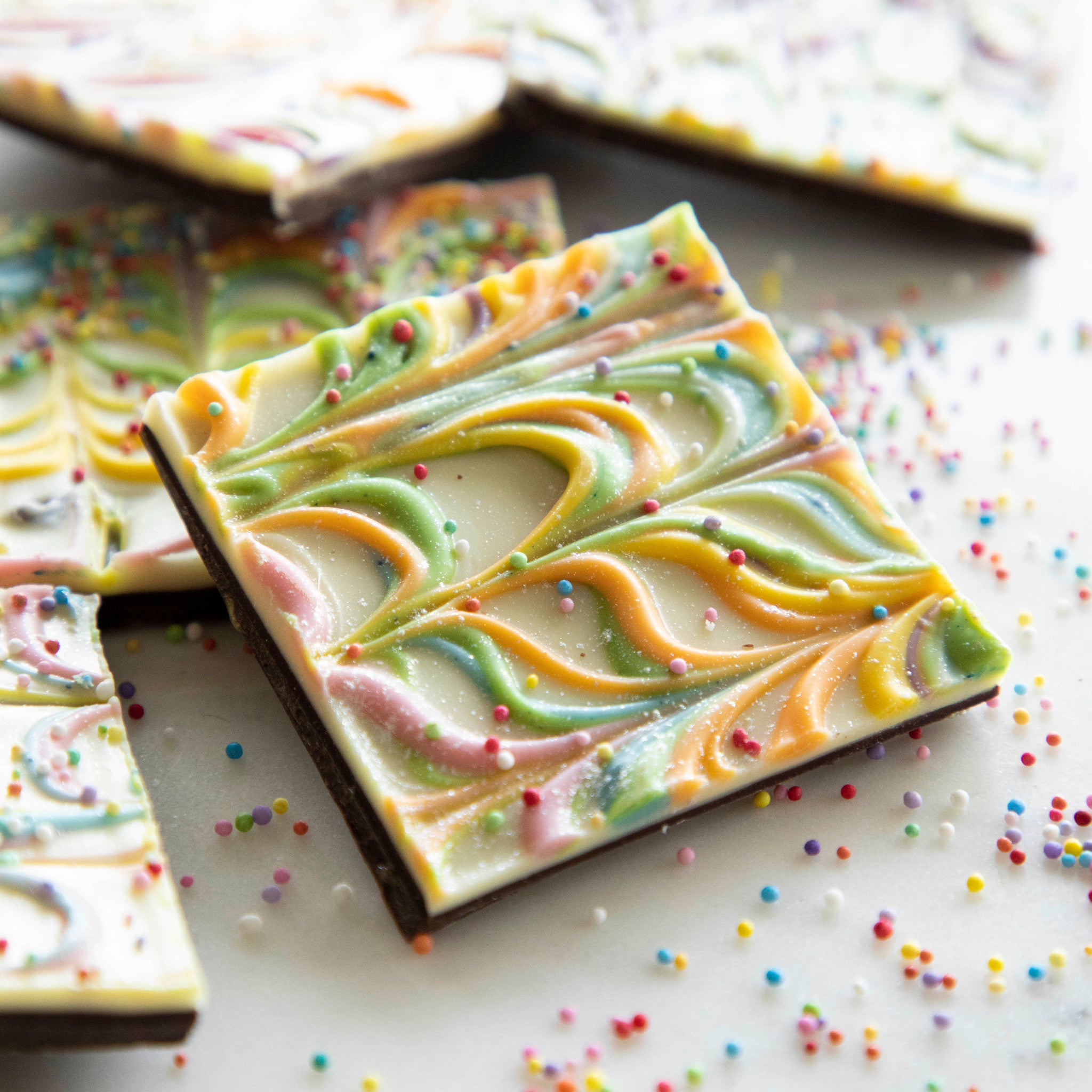 A Gluten-free Rainbow Bark with colorful swirls and sprinkles, known as Hester &amp; Cook.