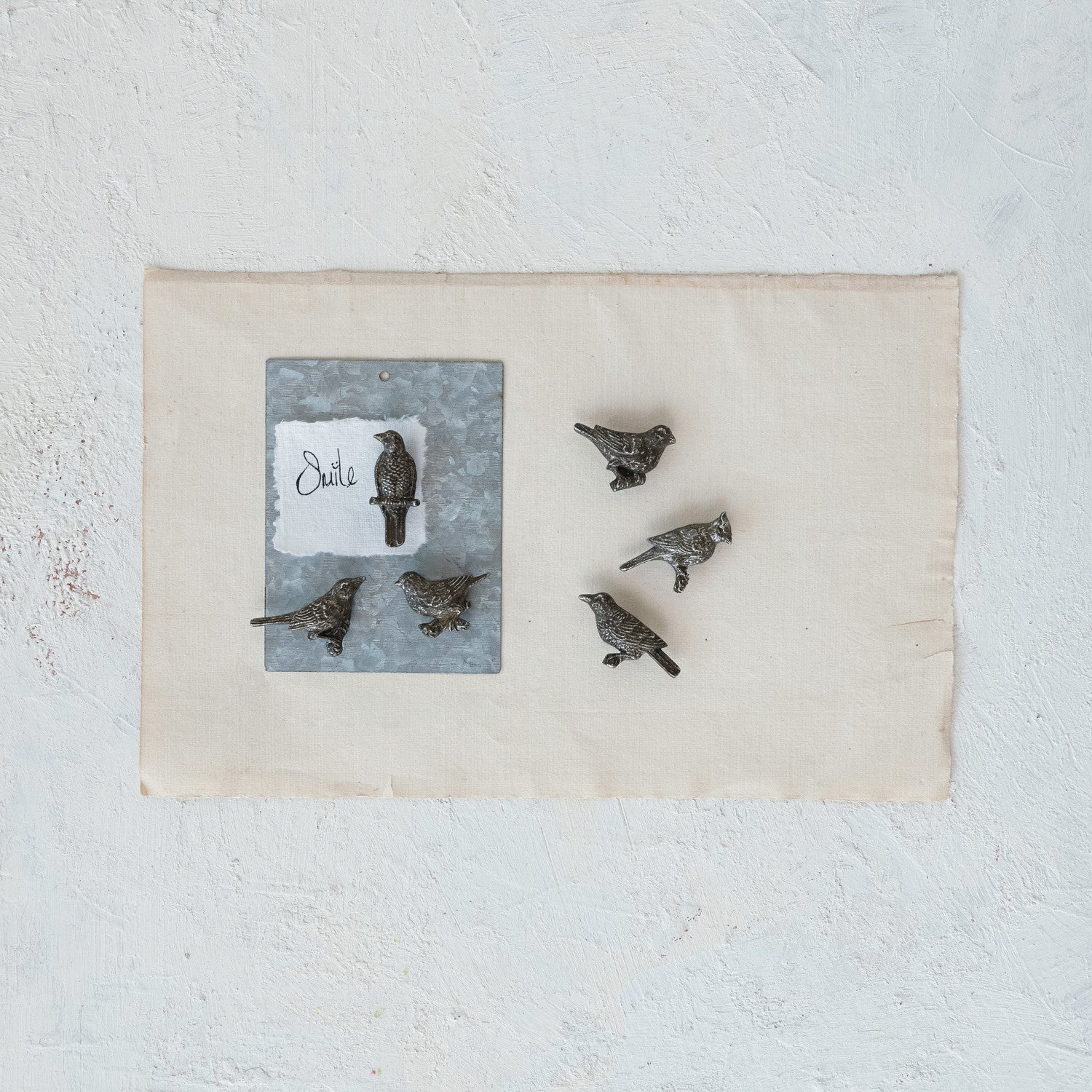 A collection of pewter bird-shaped magnets displayed on a surface.