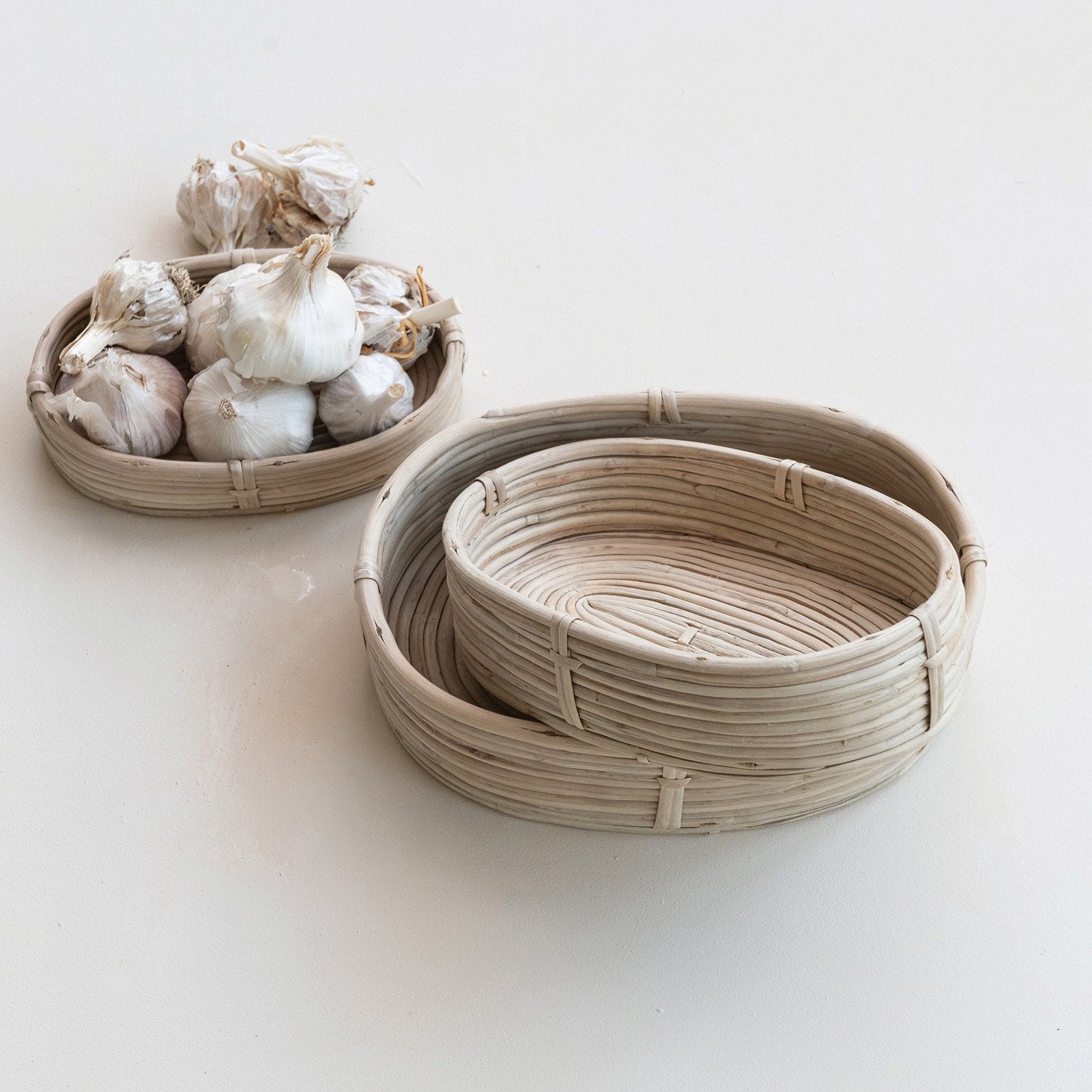 Woven baskets with garlic on a light background