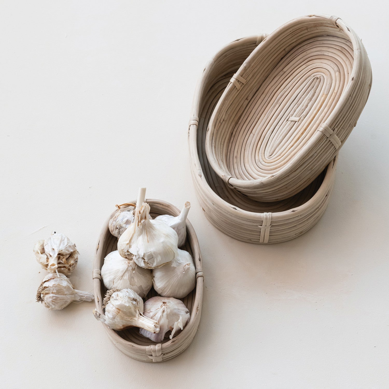 Three woven baskets with garlic on a light background