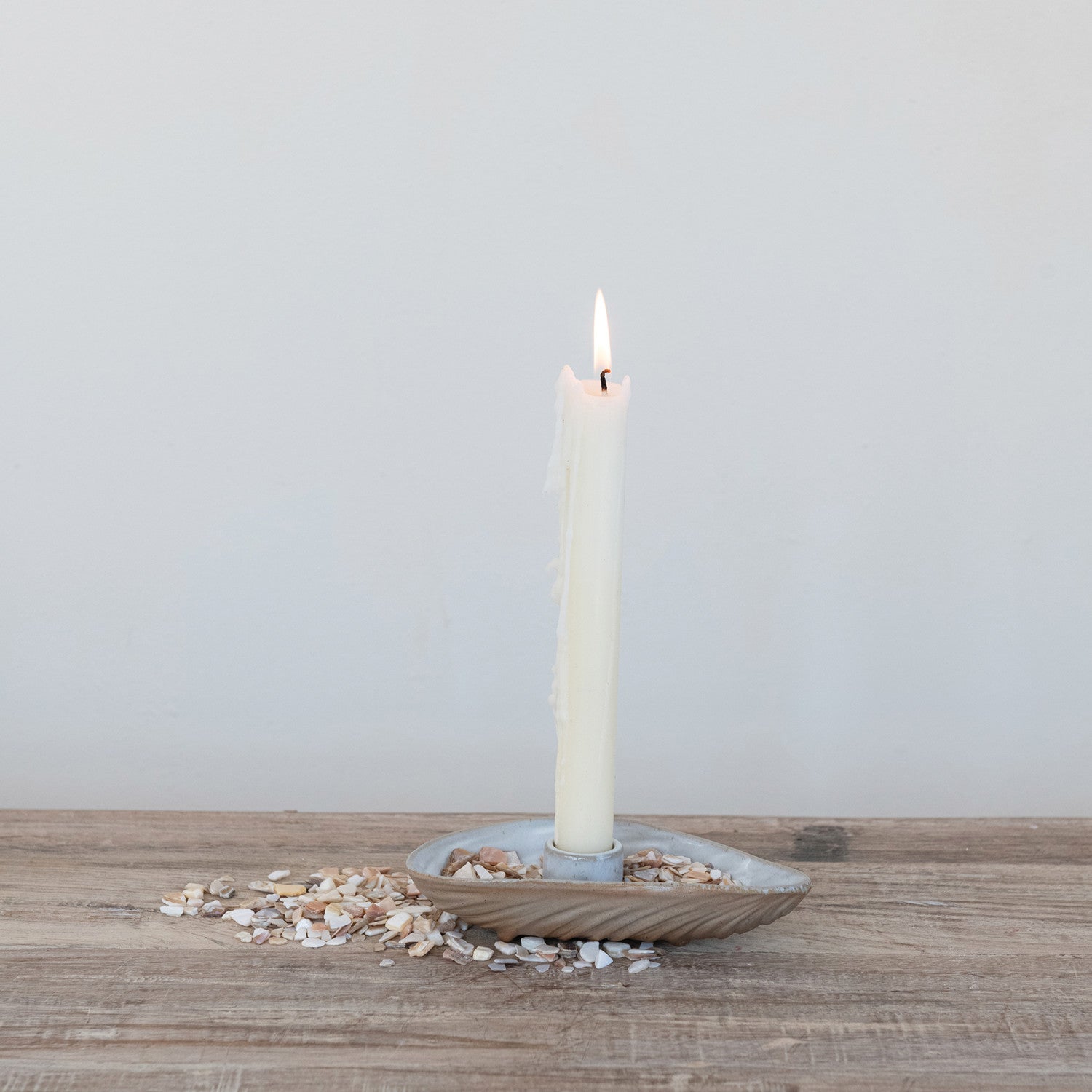 Candle in a decorative holder on a wooden surface with a light gray background