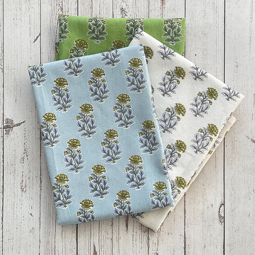 Three fabric kitchen towels with floral patterns on a wooden surface.