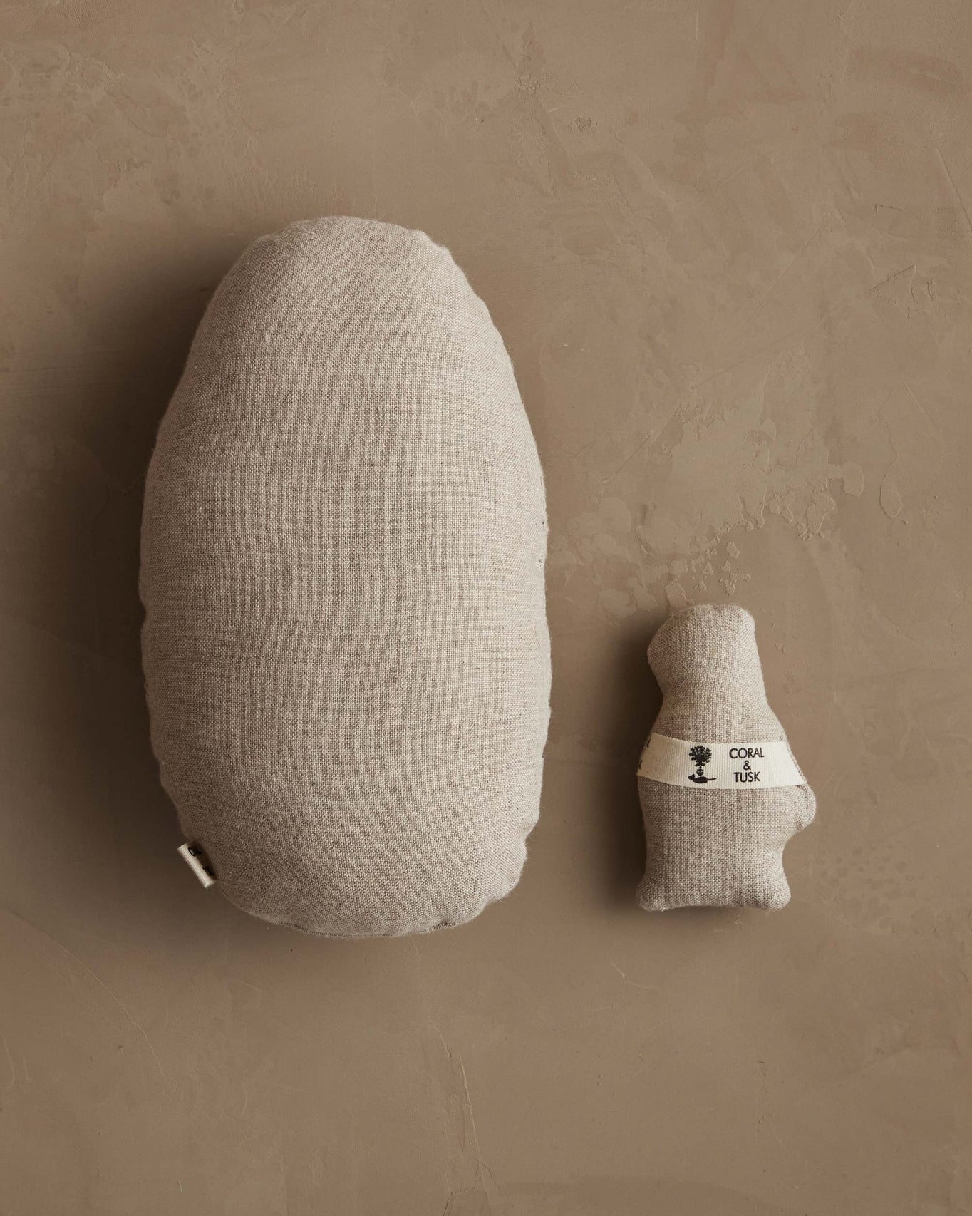 Two beige cushions, one large and one small, on a brown background.