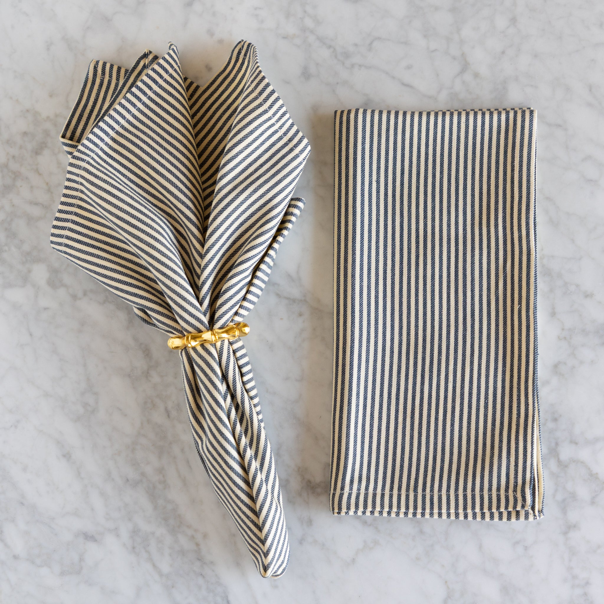 Striped napkin with a gold ring on a marble surface.