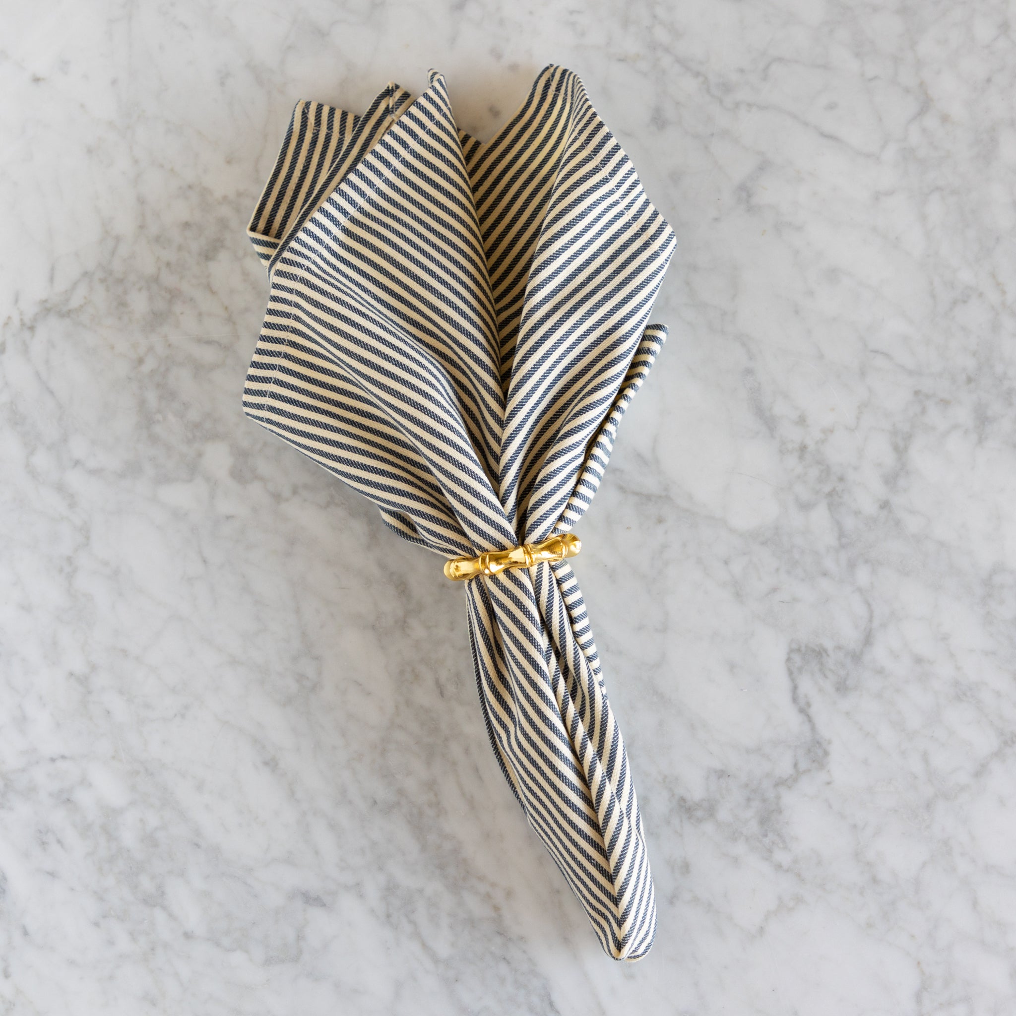 Striped napkin with a gold tie on a marble surface.