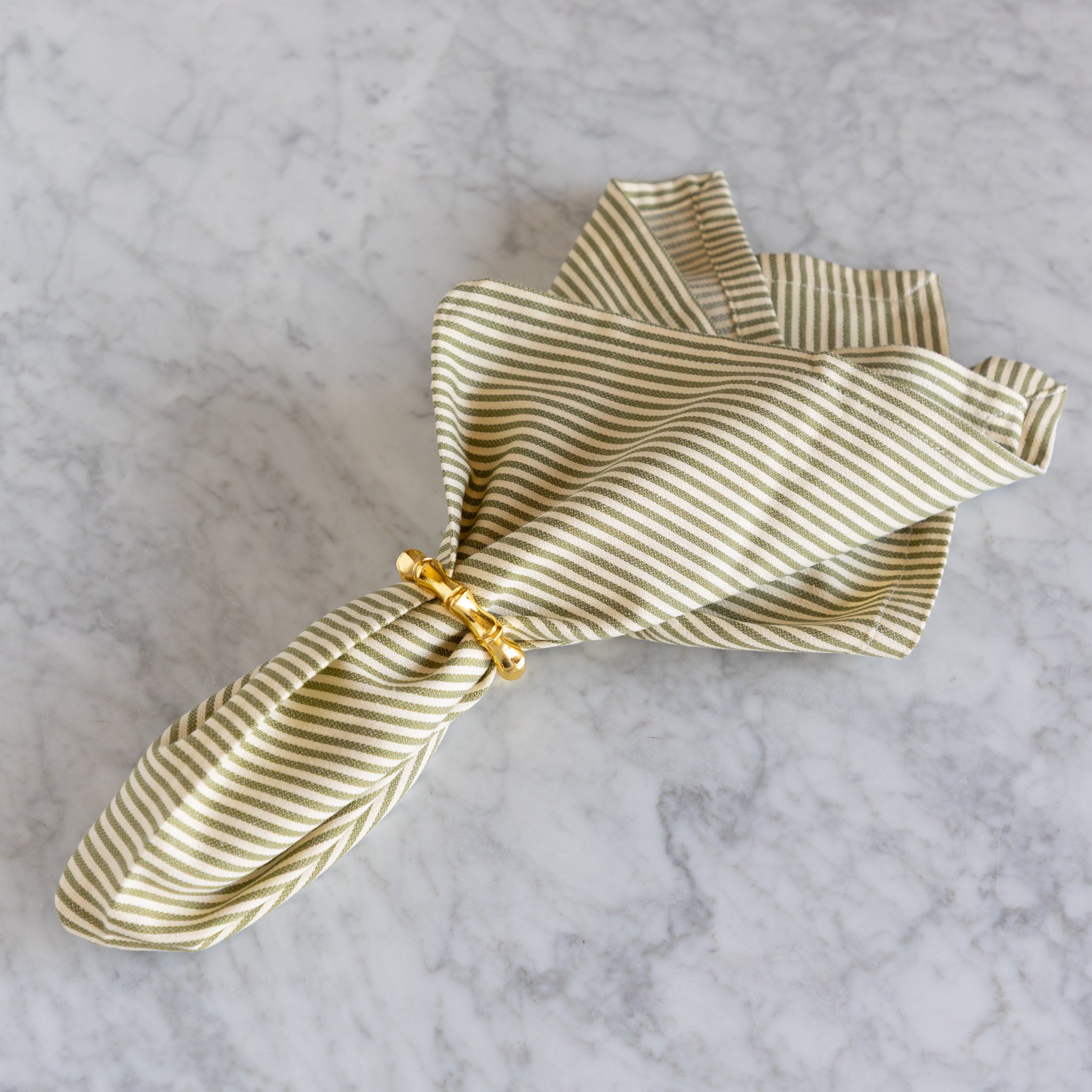 Striped fabric with a gold napkin ring on a marble surface.