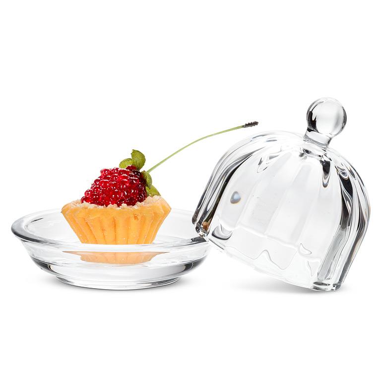 Clear glass dessert dish with a tartlet and a cherry, accompanied by a matching glass lid on a white background.
