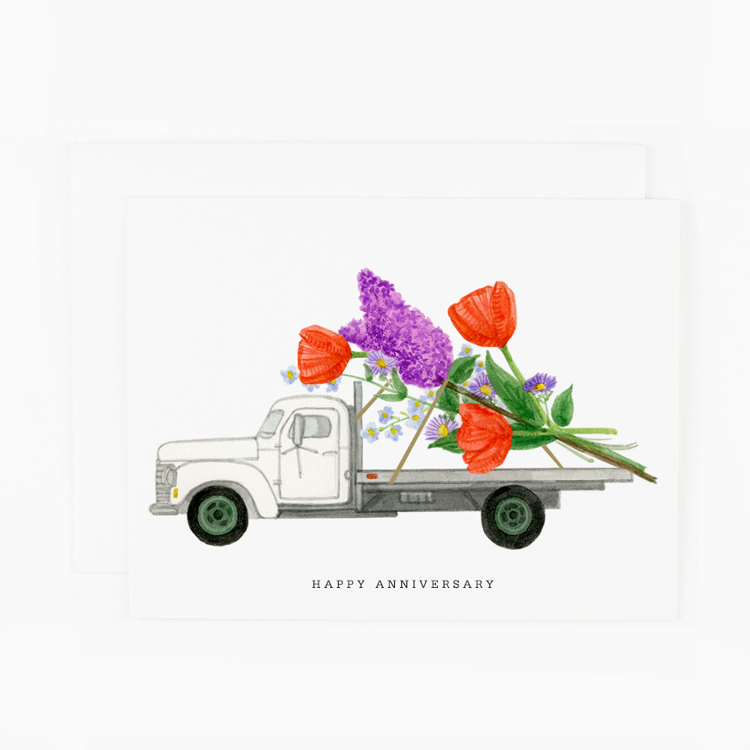 A greeting card with a giant bouquet of tulips, lilacs and wildflowers on the back of a vintage truck.
