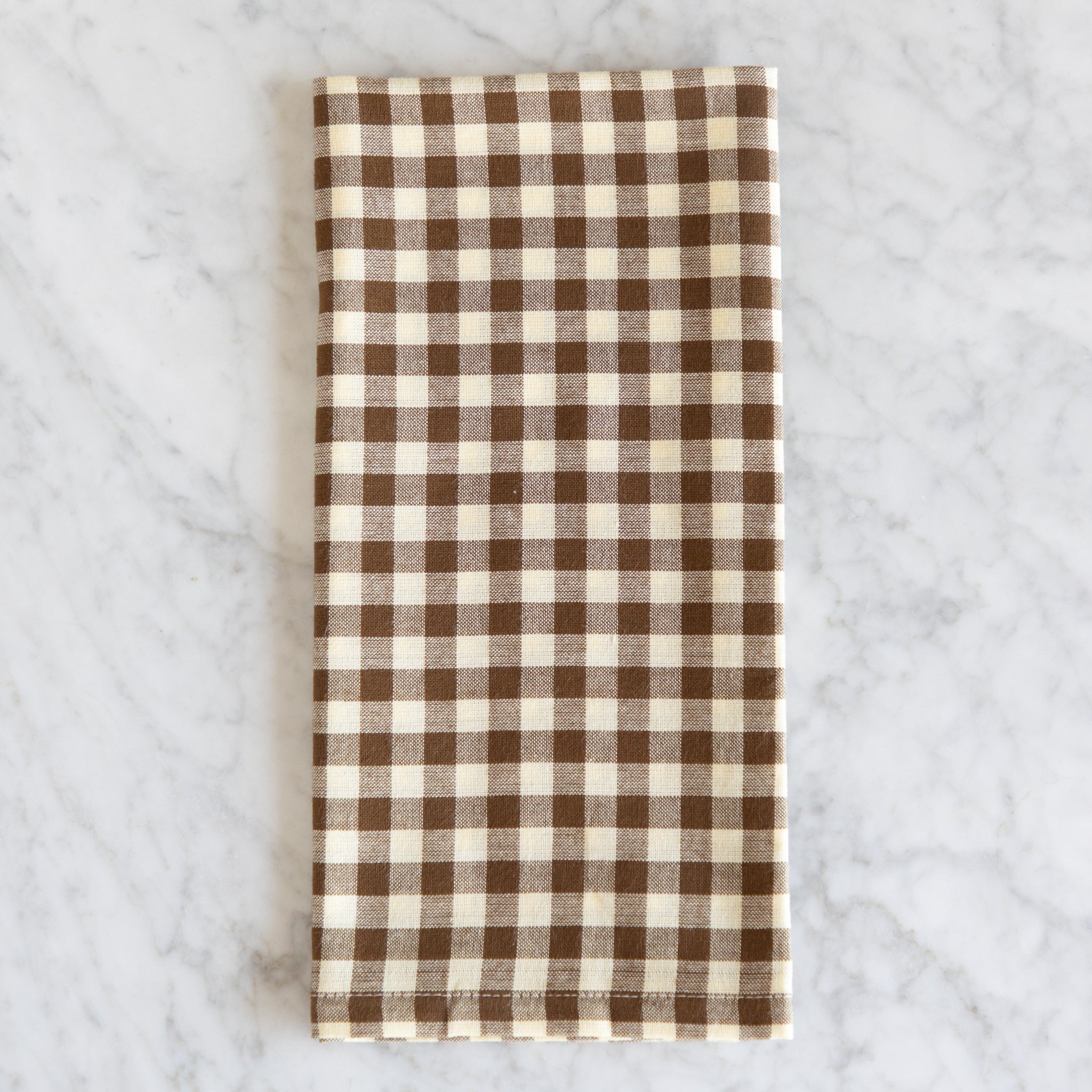 Brown and white checkered napkin on a marble surface.