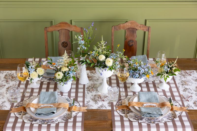A dining table set with paper table runners and placemats with a brown and white color scheme.
