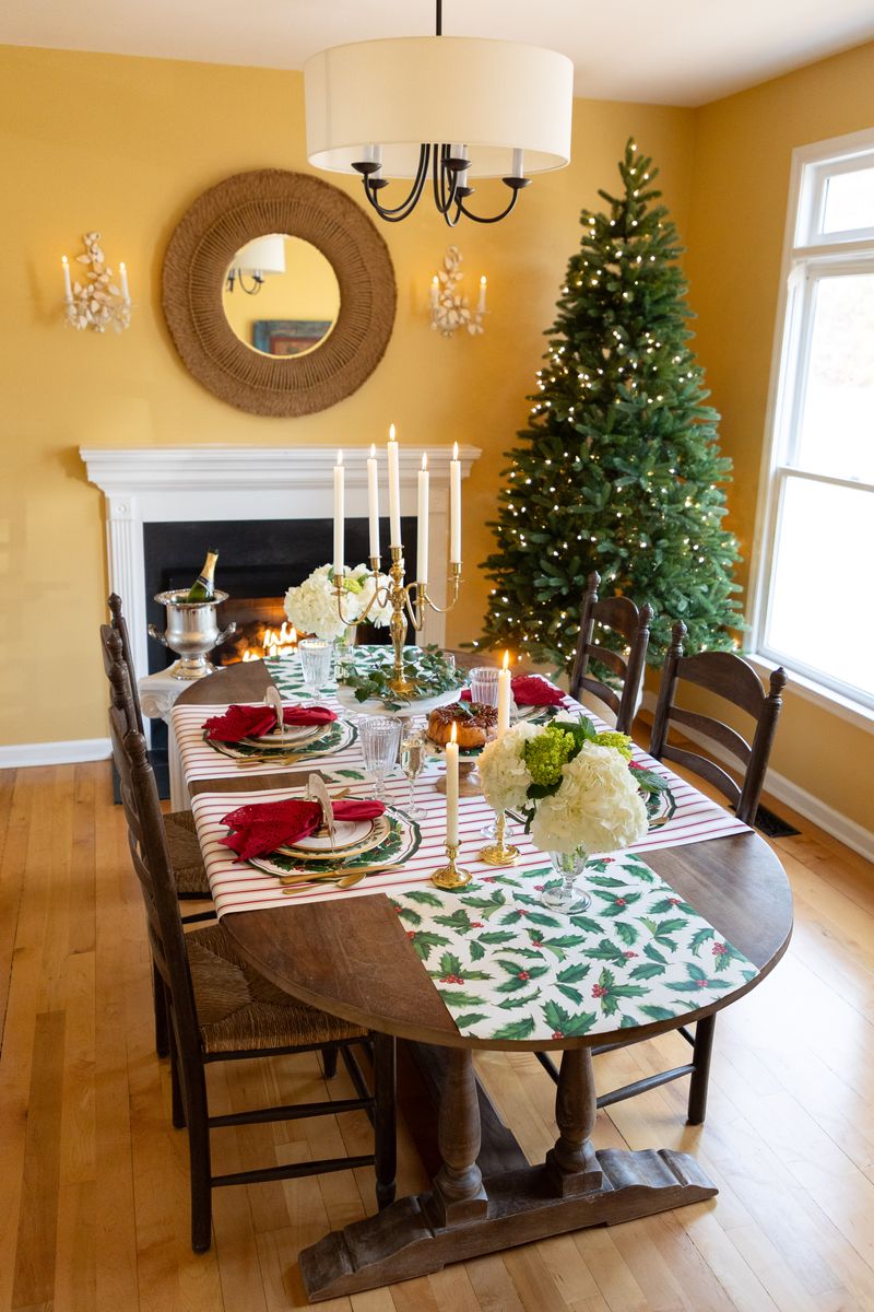 Dining room with a Christmas tree, table set for dinner, and fireplace.