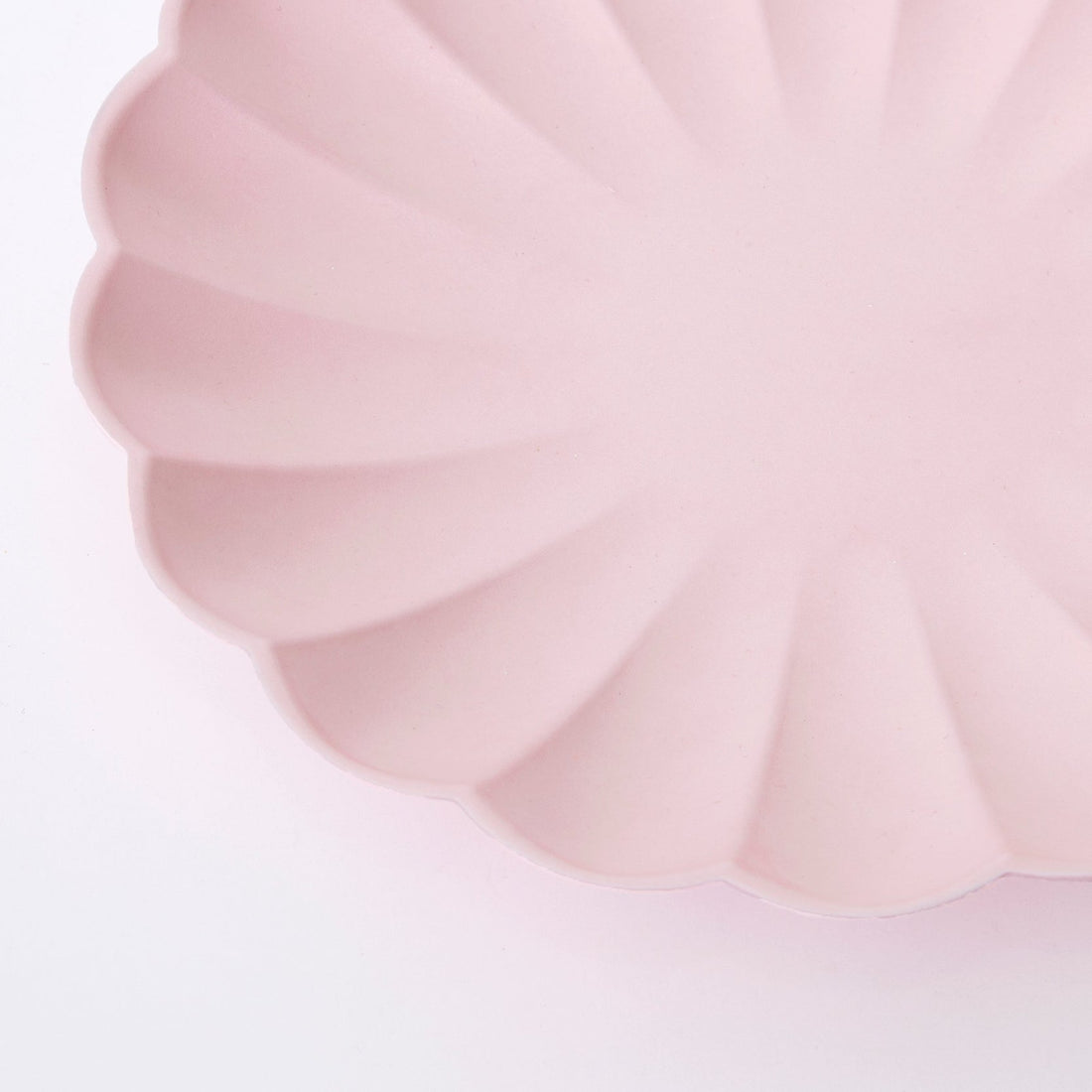 A Meri Meri Pale Pink Eco Plate in the shape of a flower on a white background.