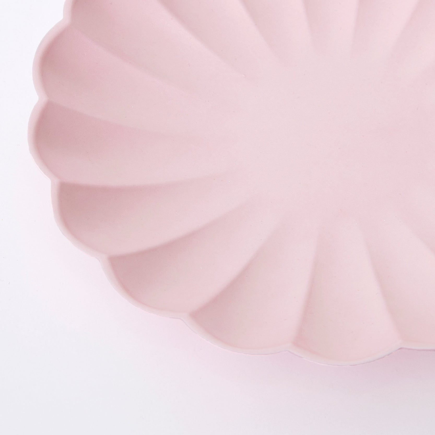 A Meri Meri Pale Pink Eco Plate in the shape of a flower on a white background.