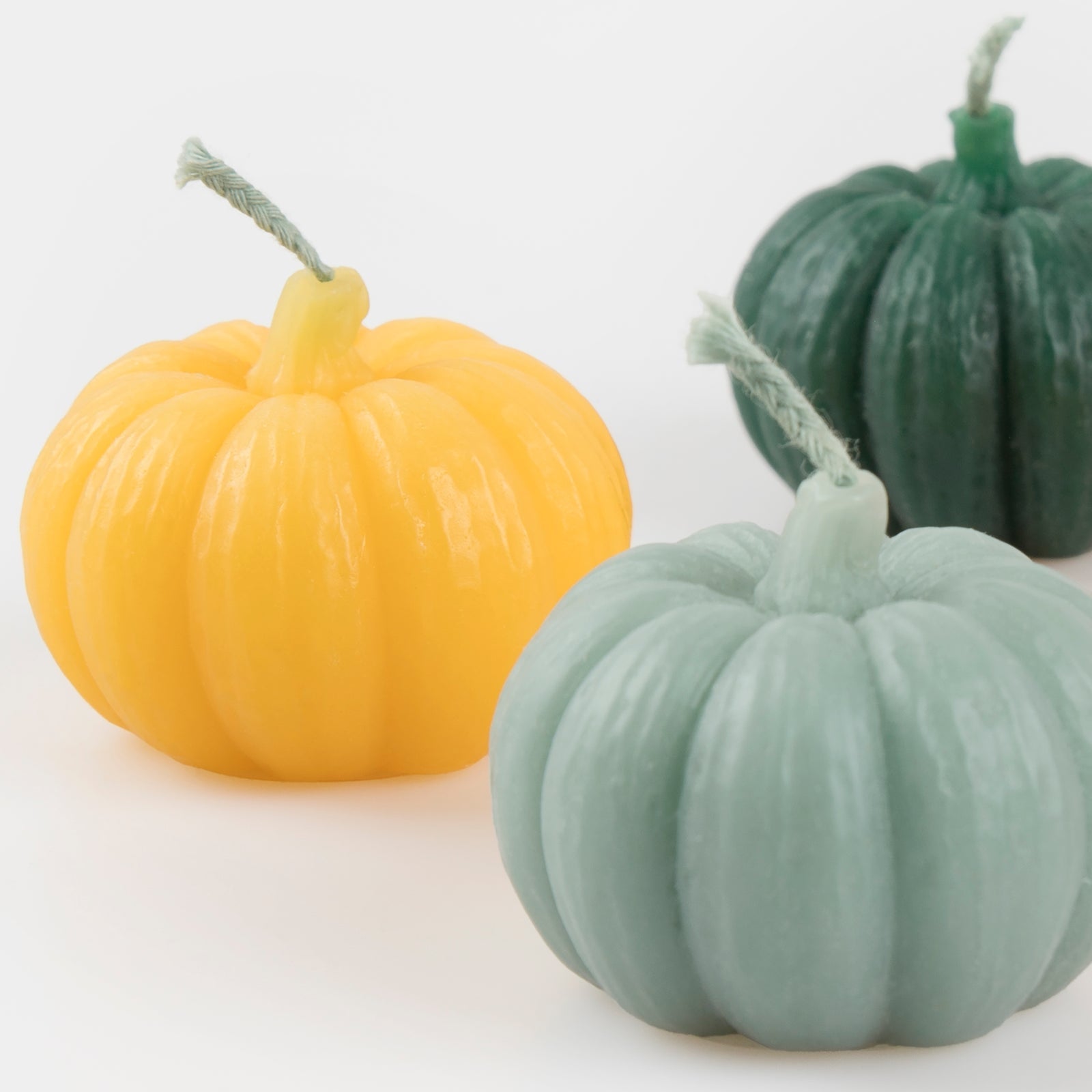Pumpkin-shaped candles in multiple colors.