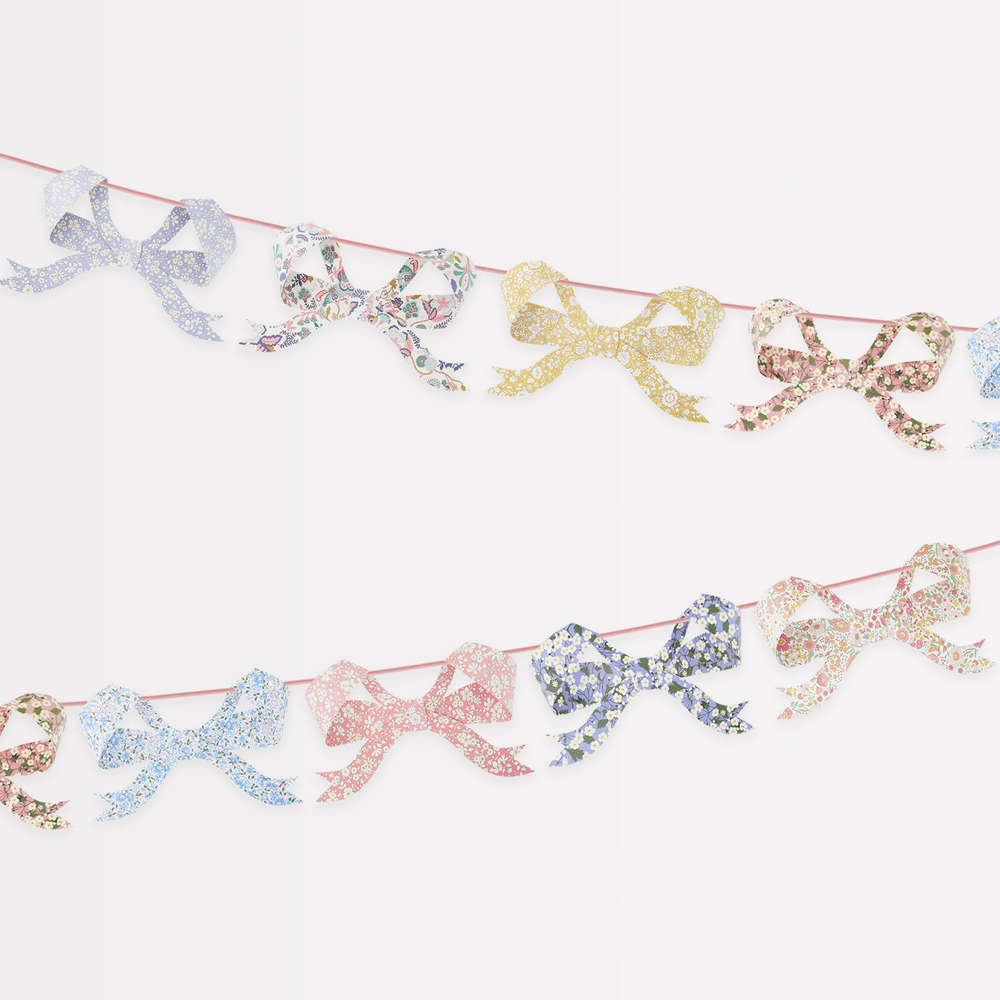 Eight bow pennants in floral Liberty print designs strung on ribbon.