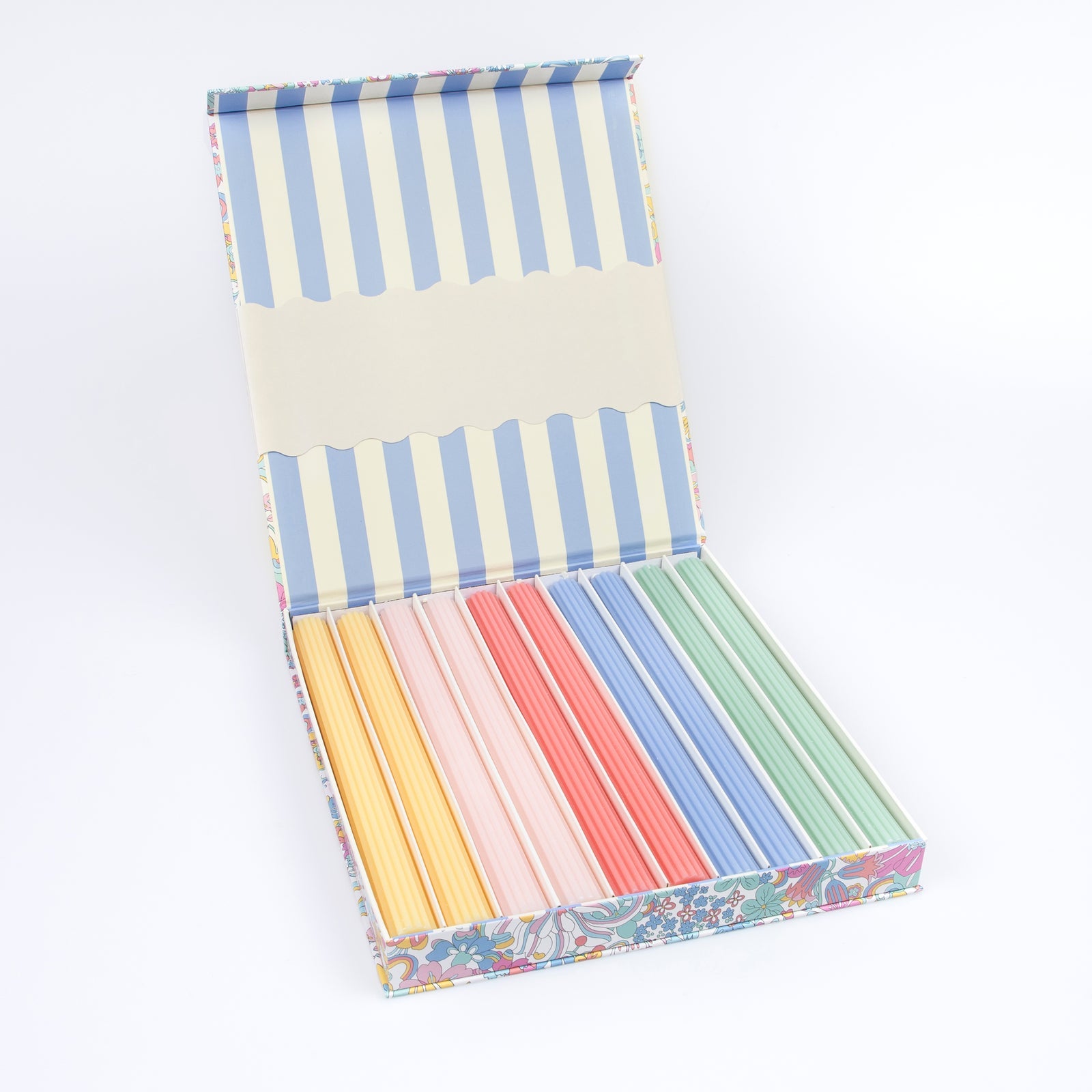 A floral box opened to show colorful tapper candles and a blue-and-white striped pattern inside the box.