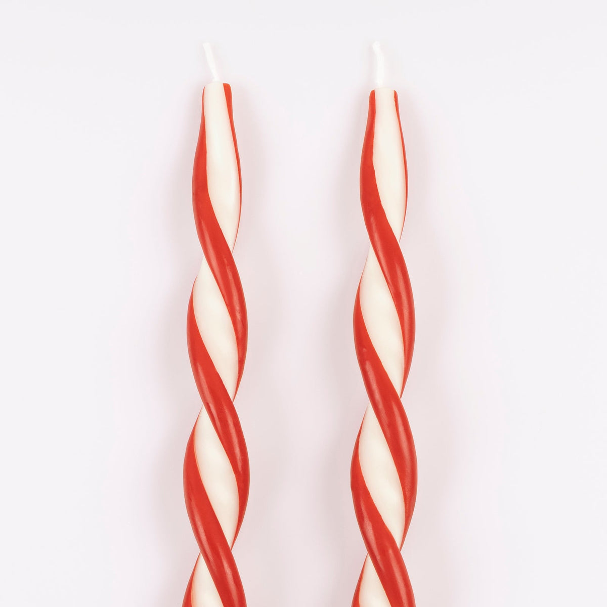 Two red and white striped candles on a white background.