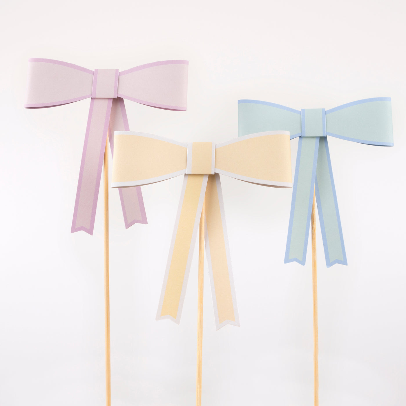 Mint, yellow and peach paper bow cake toppers on bamboo skewers.