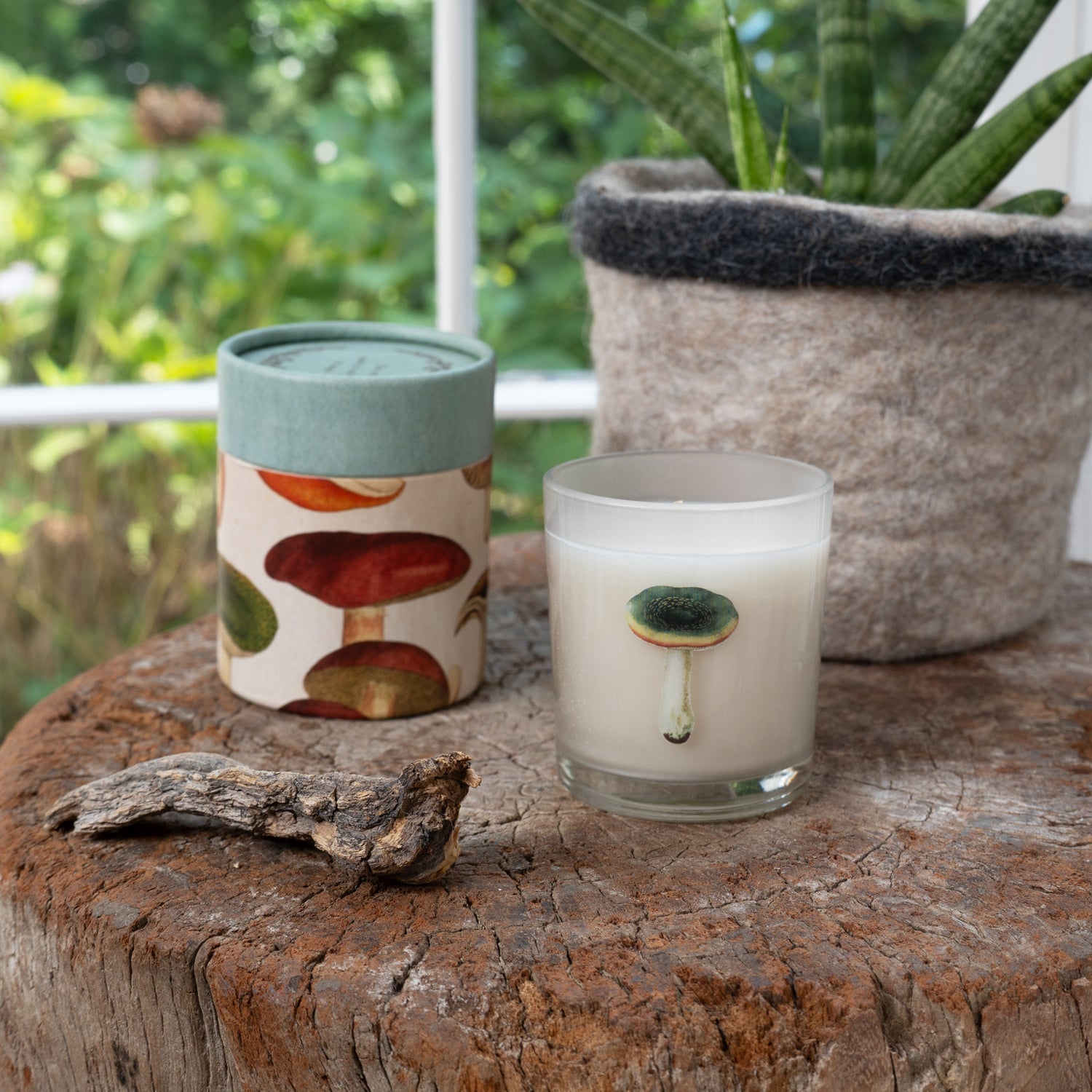 Candle with mushroom design on a wooden surface outdoors.