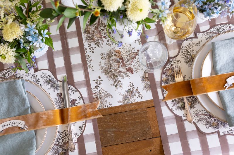 Decorative table setting with floral arrangements, checkered tablecloth, and patterned placemats.