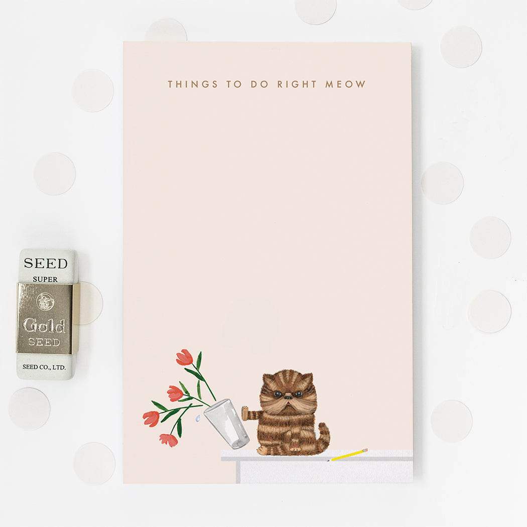 Dear Hancock notepad with a brown striped cat pushing a vase of flowers off a table and text that reads &quot;Things to do right meow&quot;.