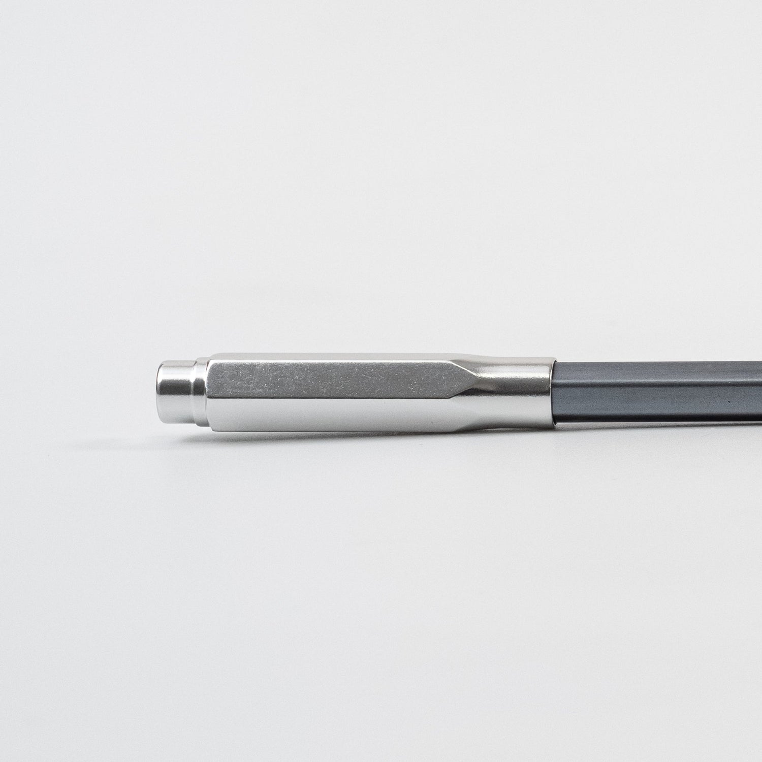 A black, gold, and silver Blackwing Point Guard sits on a white surface next to a Blackwing pencil.